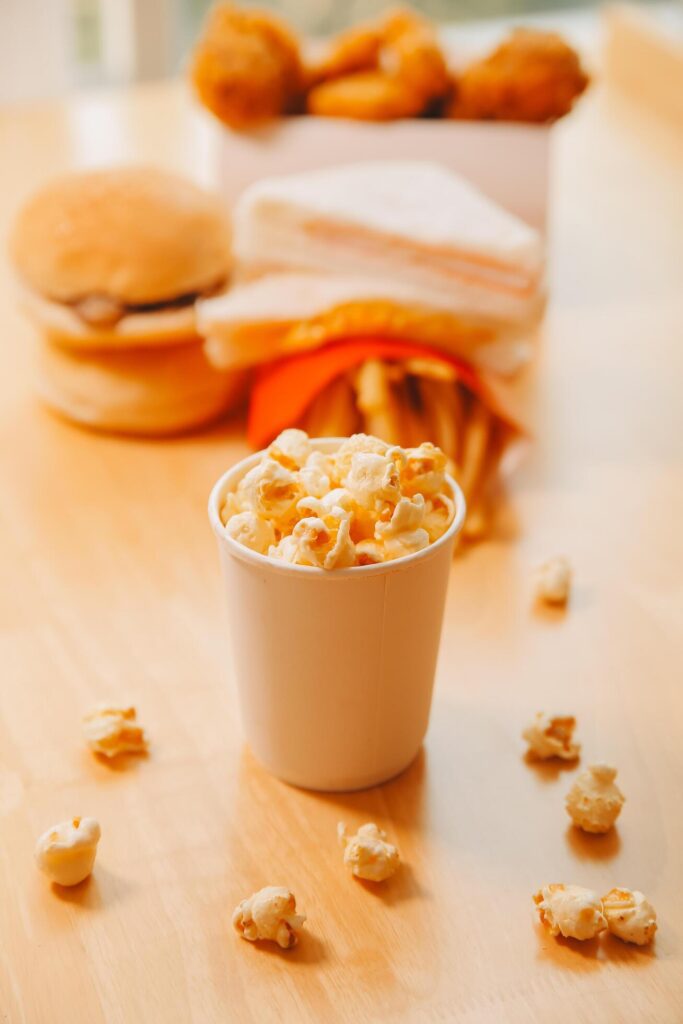 A bucket of popcorn, top-view, warm colors, light brown wooden background, flat lay, daylight macro close-up Stock Free