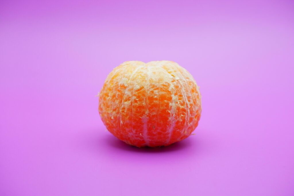 Peeled orange isolated on purple background Stock Free