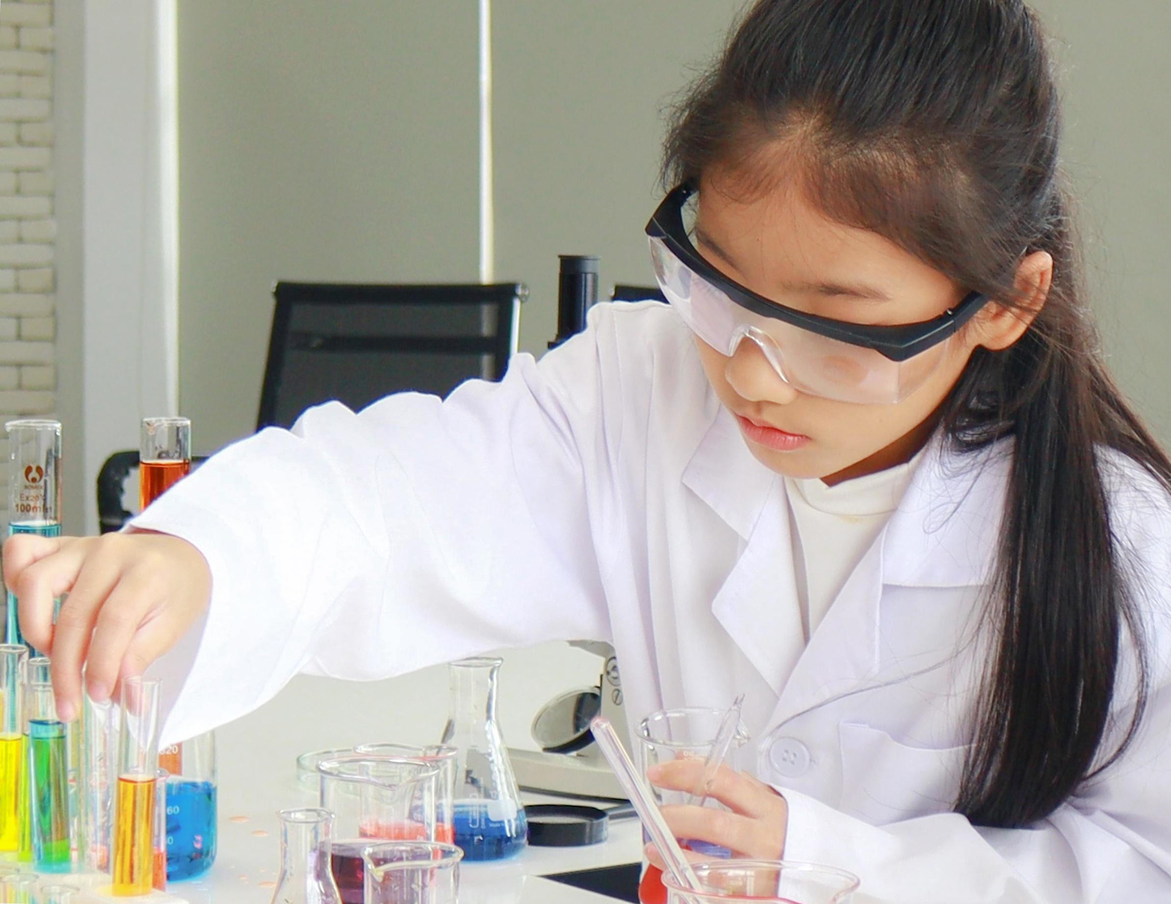 Young female student doing science experiments with a chemical tube in a laboratory Stock Free