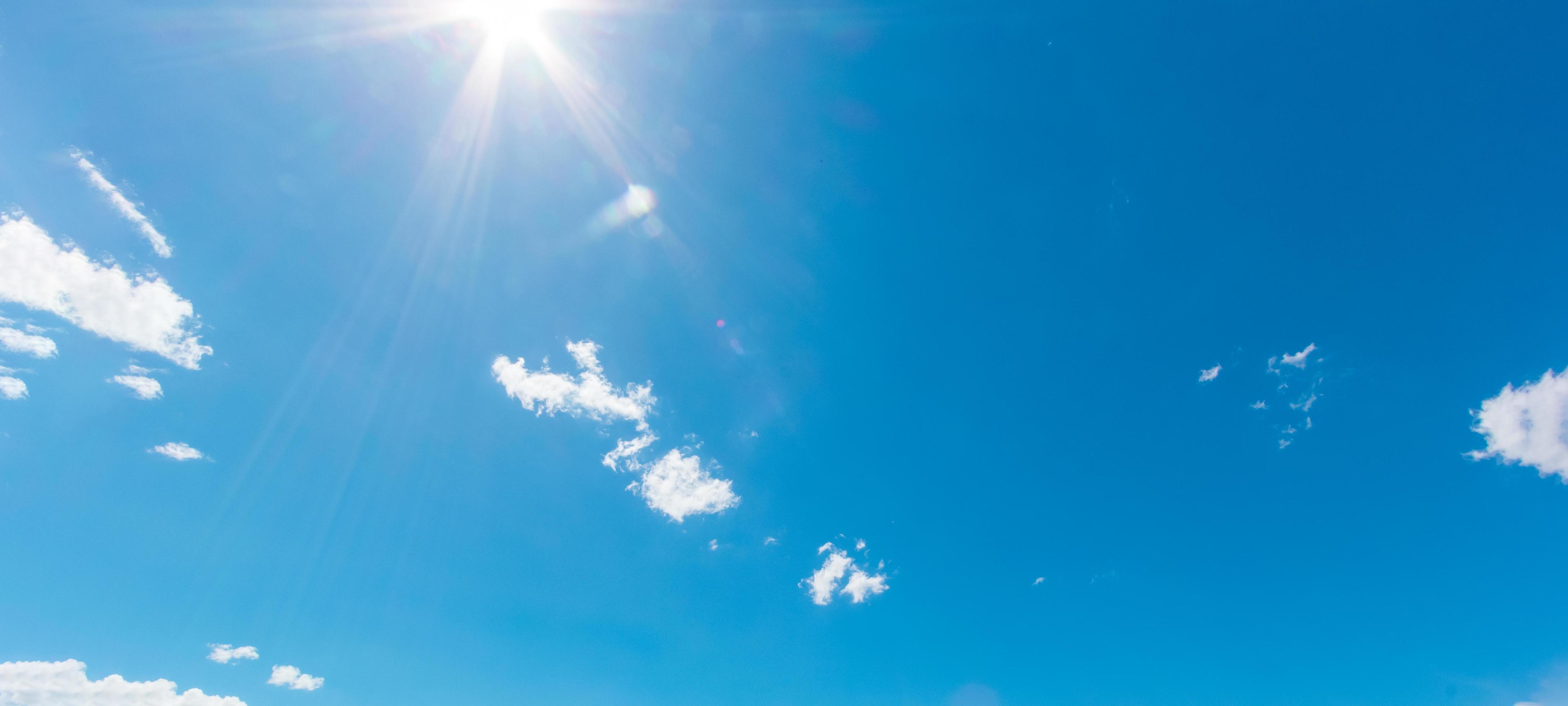 Natural abstract background of bright blue sky and fluffy white clouds on a sunny, light a flare and sun. Stock Free