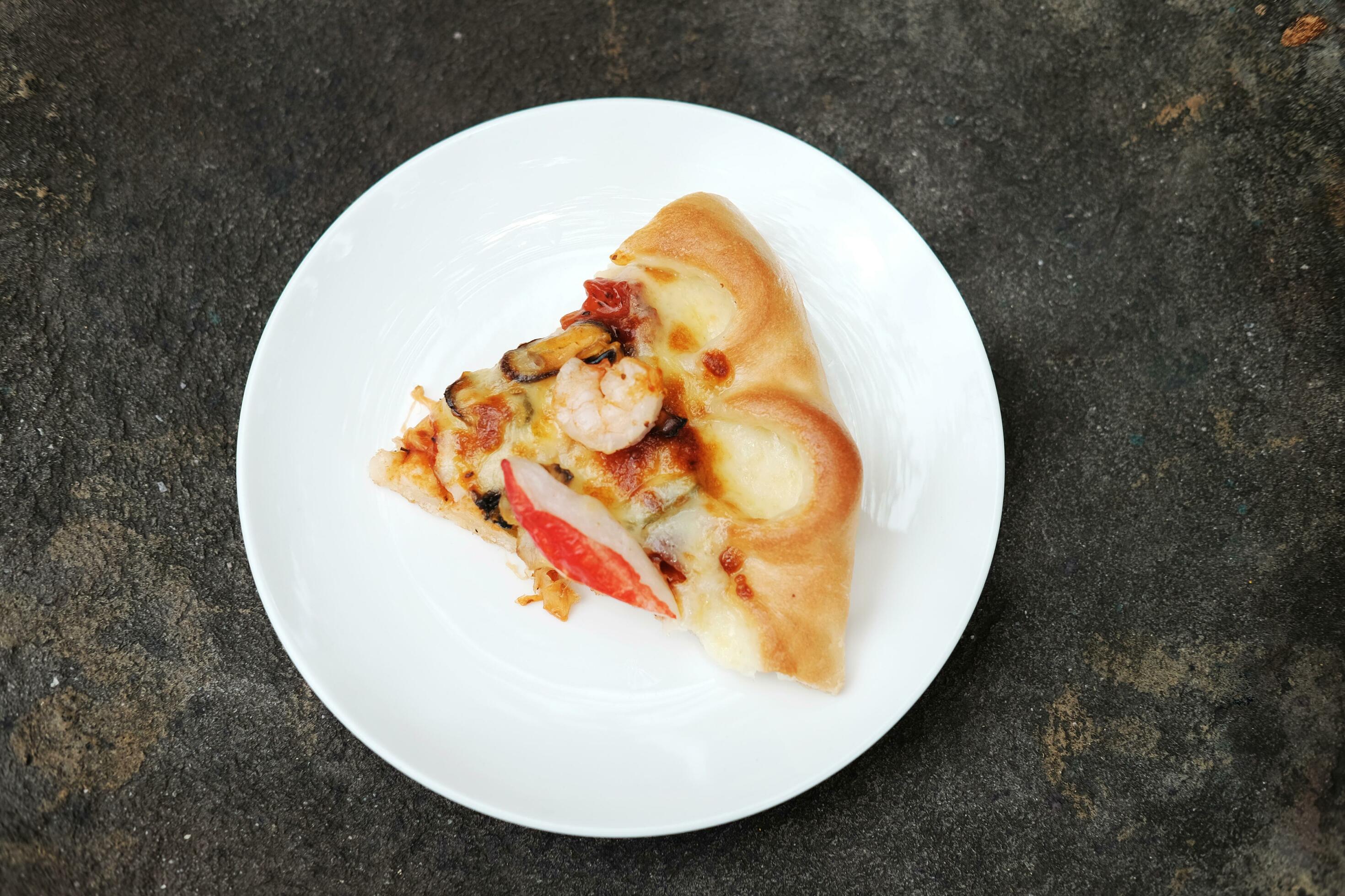 Delicious Italian food Sliced of Pizza on White dish and black concrete floor. Stock Free