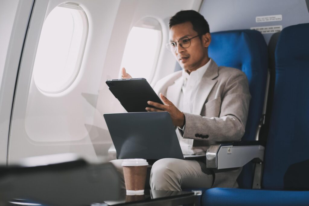 Airplane, travel and portrait of businessman working on laptop computer and smartphone while sitting in airplane. Stock Free