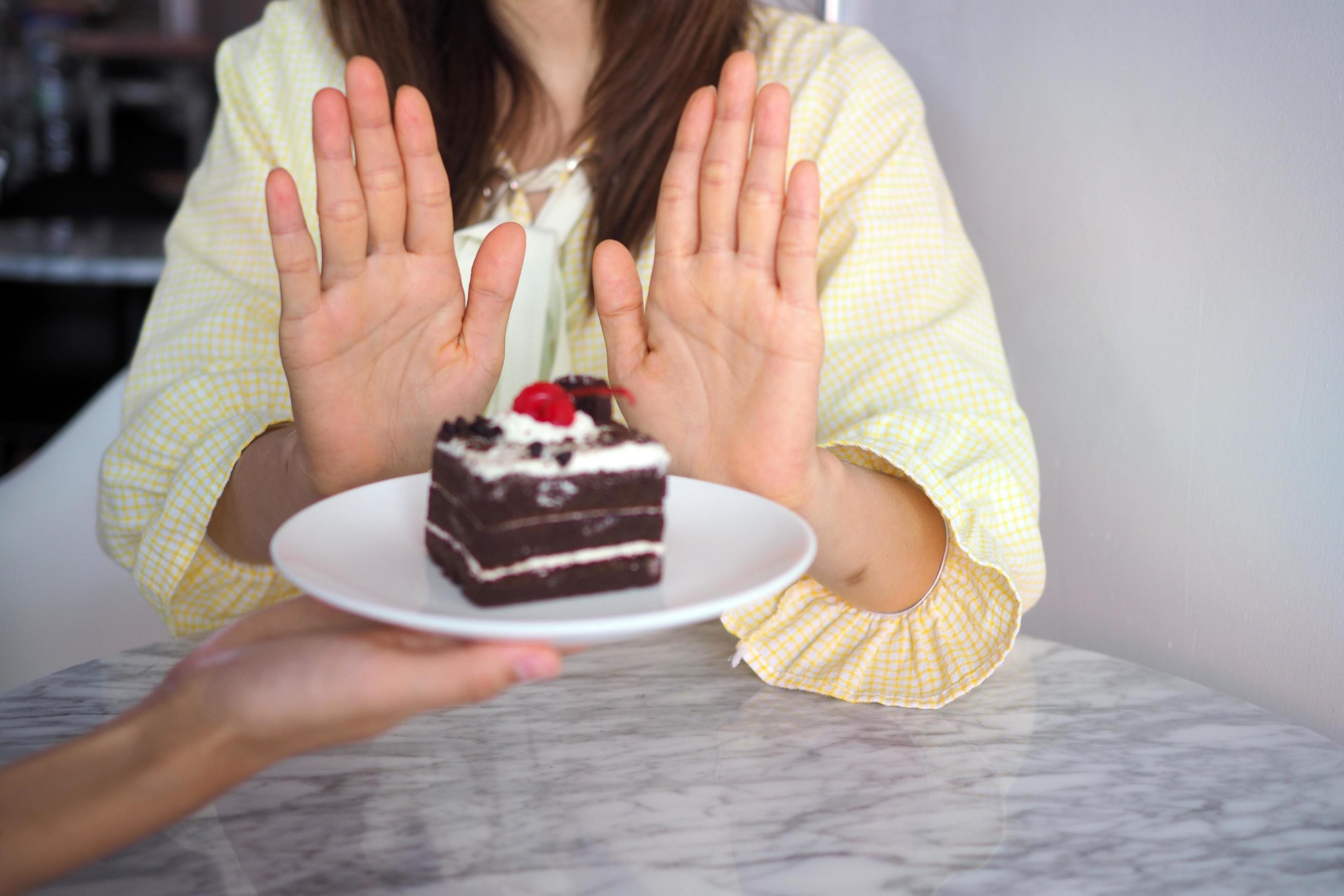 A woman in health care uses a hand to push a chocolate cake. Refused to eat foods that contain trans fats Stock Free