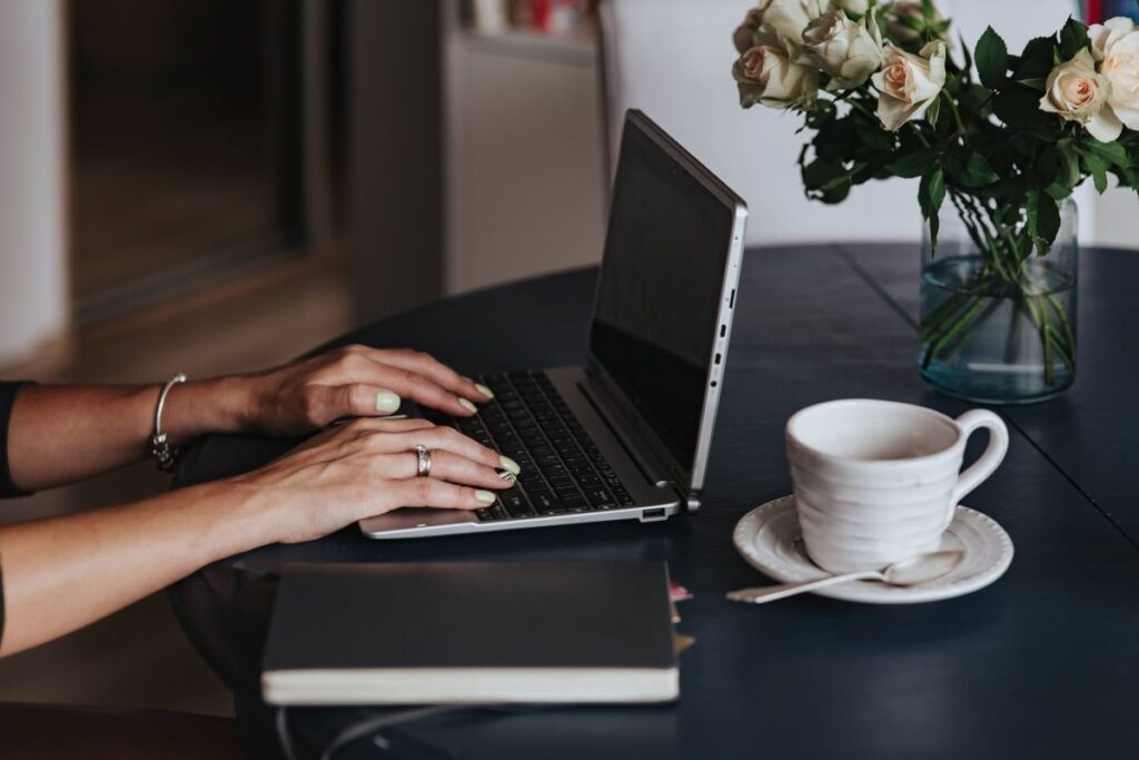 Woman using a laptop by a round breakfast table Stock Free