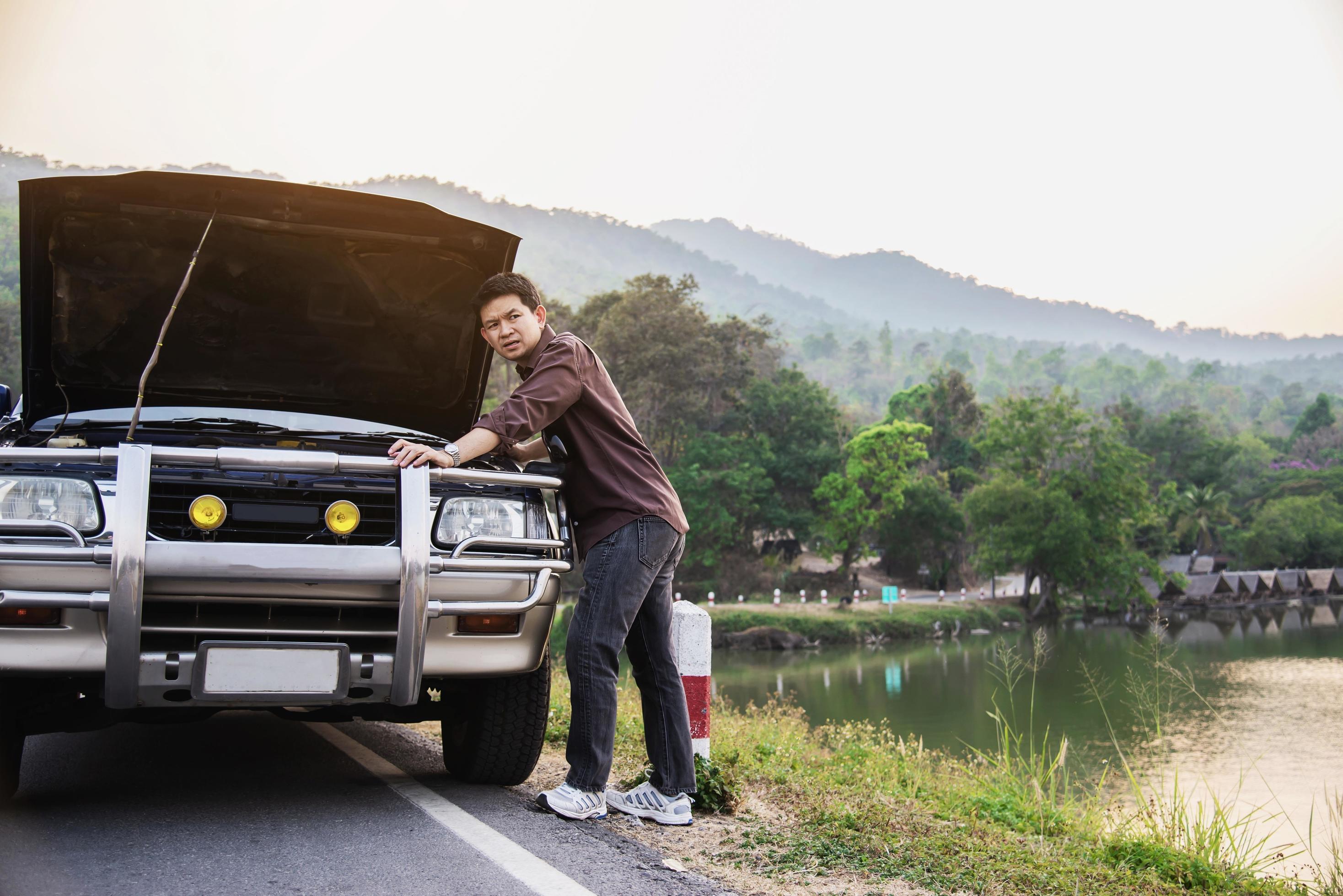 Man try to fix a car engine problem on a local road Chiang mai Thailand – people with car problem transportation concept Stock Free