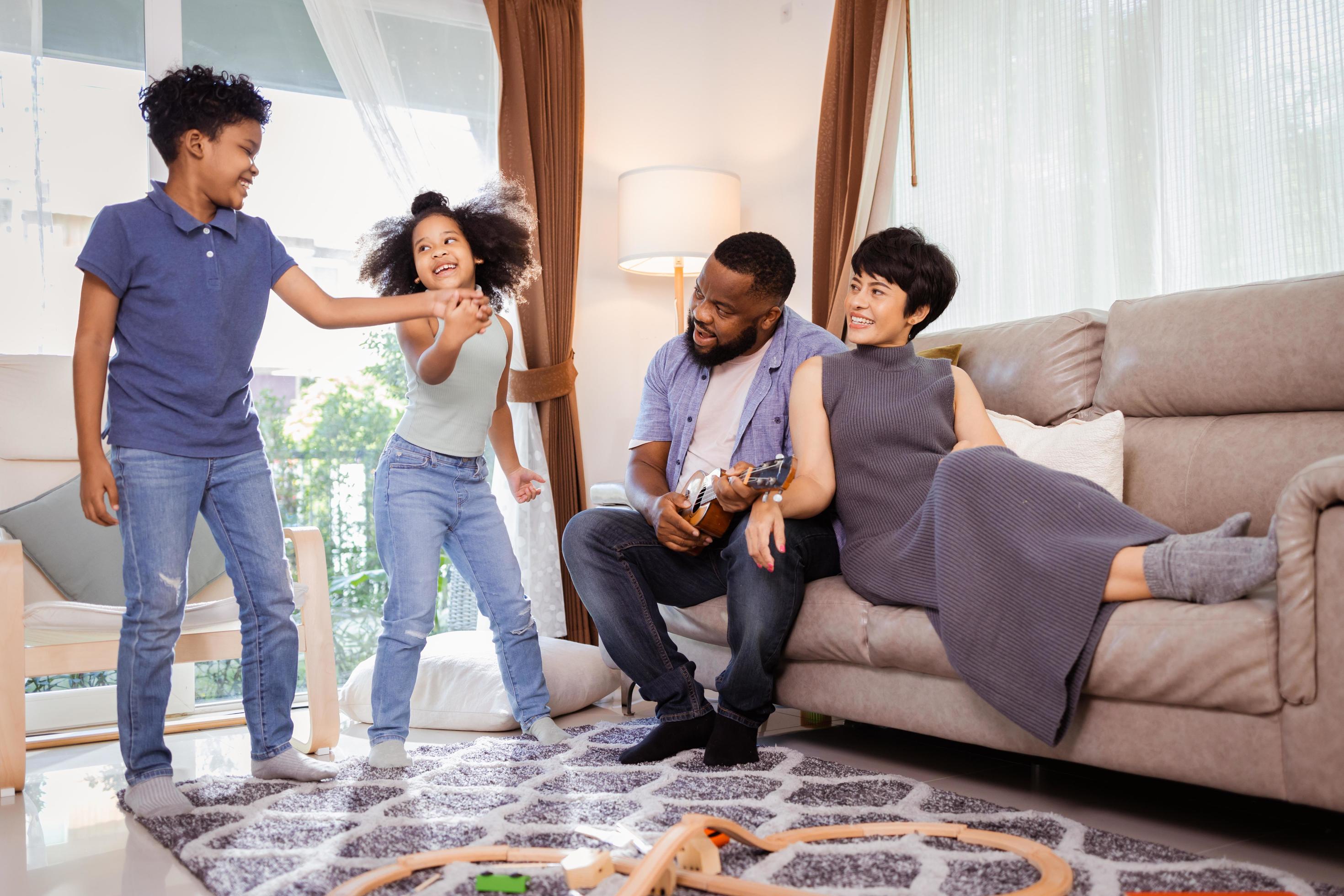 Happy African American family with little kids boy and girl dancing in the living room Stock Free