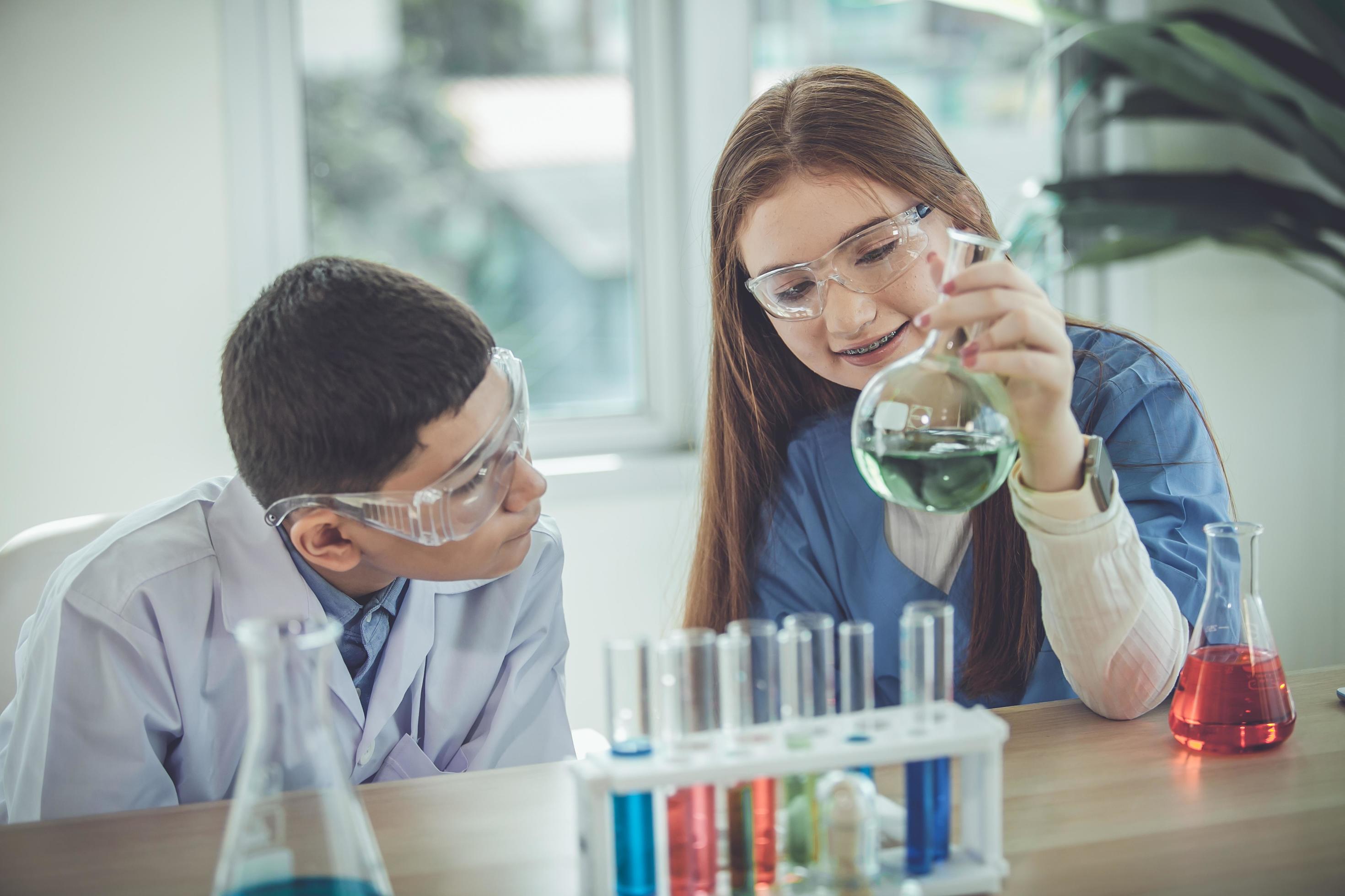 Students mixes chemicals in beakers. Chemistry student mixes chemicals in science class Stock Free