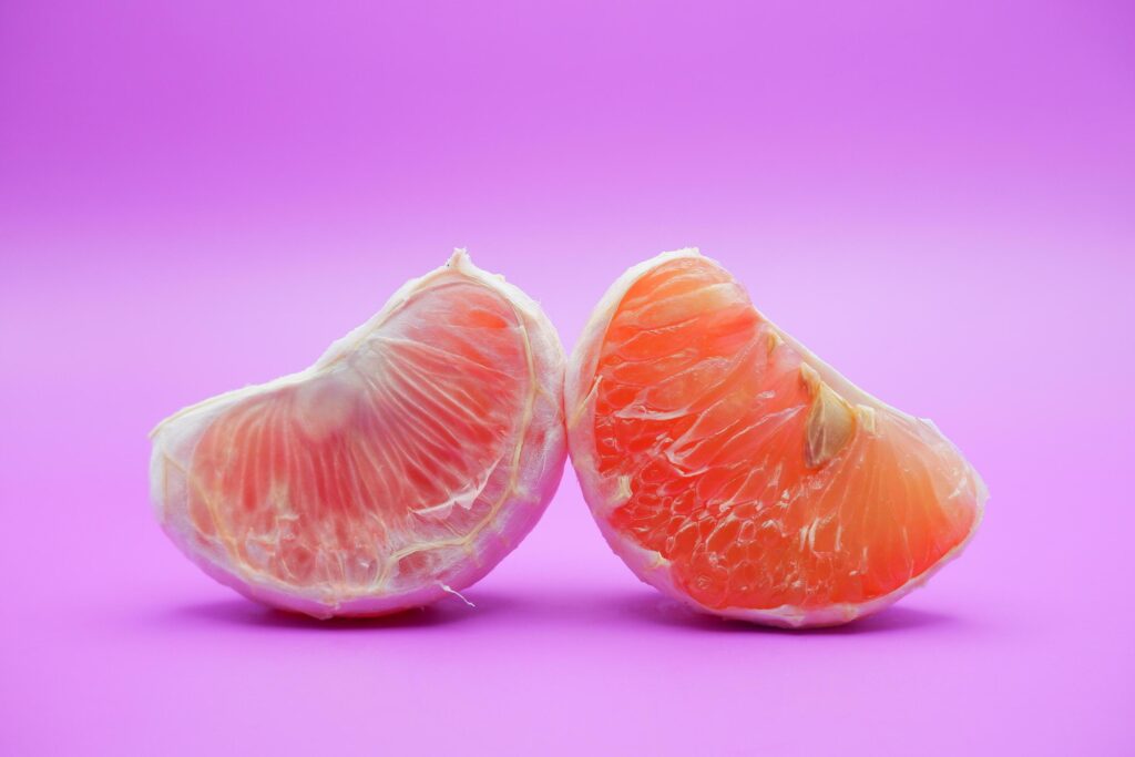 2 grapefruit isolated on purple background. 2 pieces of grapefruit that have been peeled until the grain of the orange is visible Stock Free