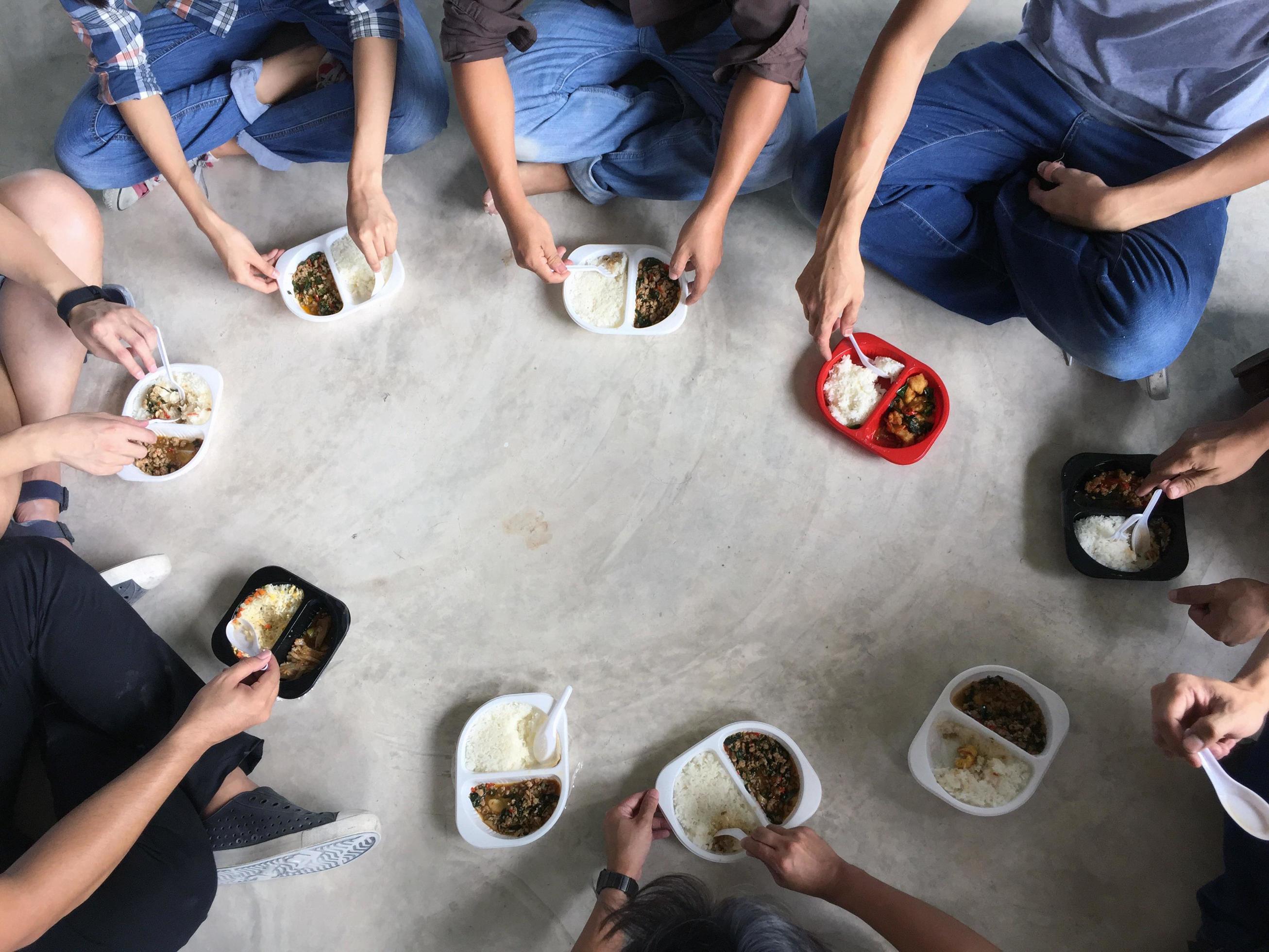 The group of employees sat in a circle, eating a box of fast-food together. Stock Free