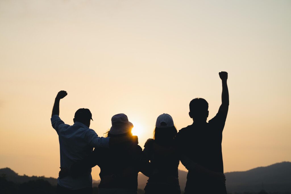 group of people with raised arms looking at sunrise on the mountain background. Happiness, success, friendship and community concepts. Stock Free