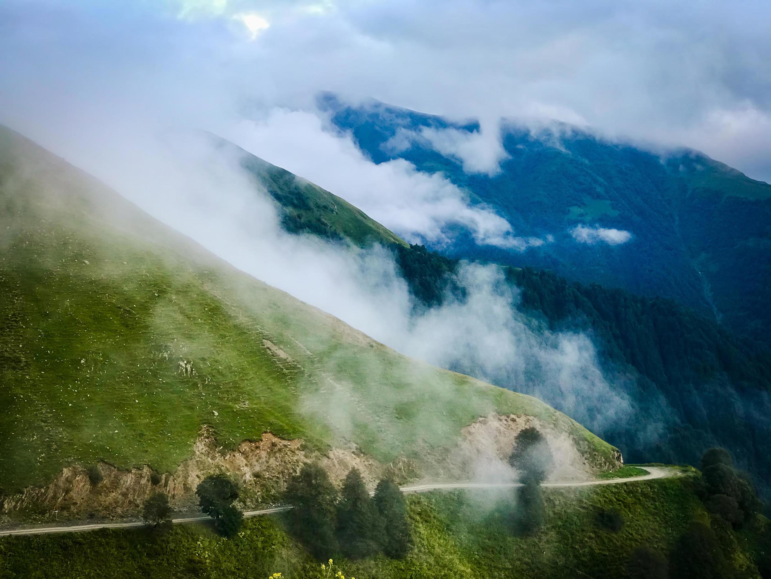 Scenic mountain gravel road in Tusheti region surrounded by foggy caucasus nature Stock Free