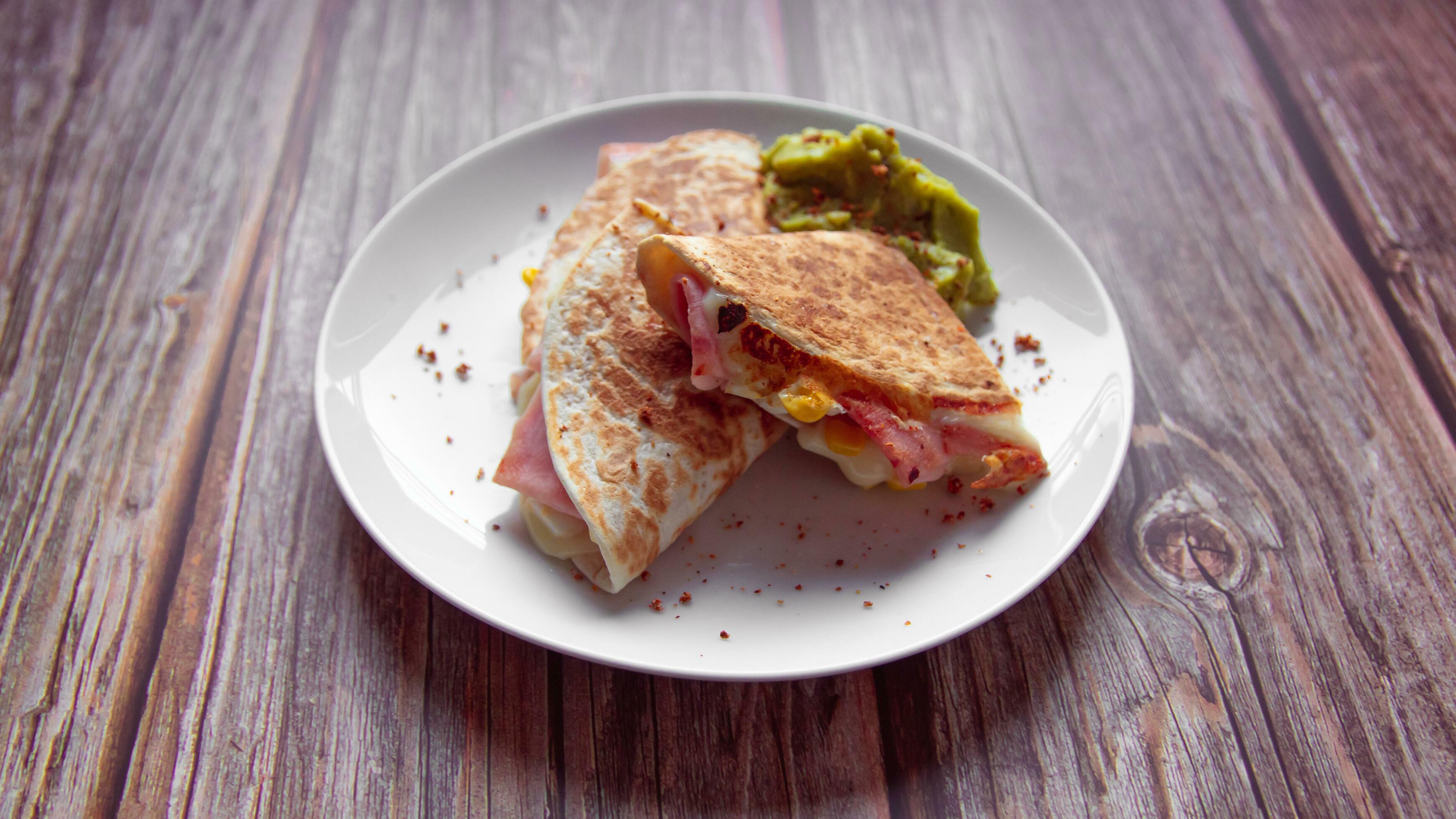 A plate of food with a quesadilla and guacamole on it. Stock Free