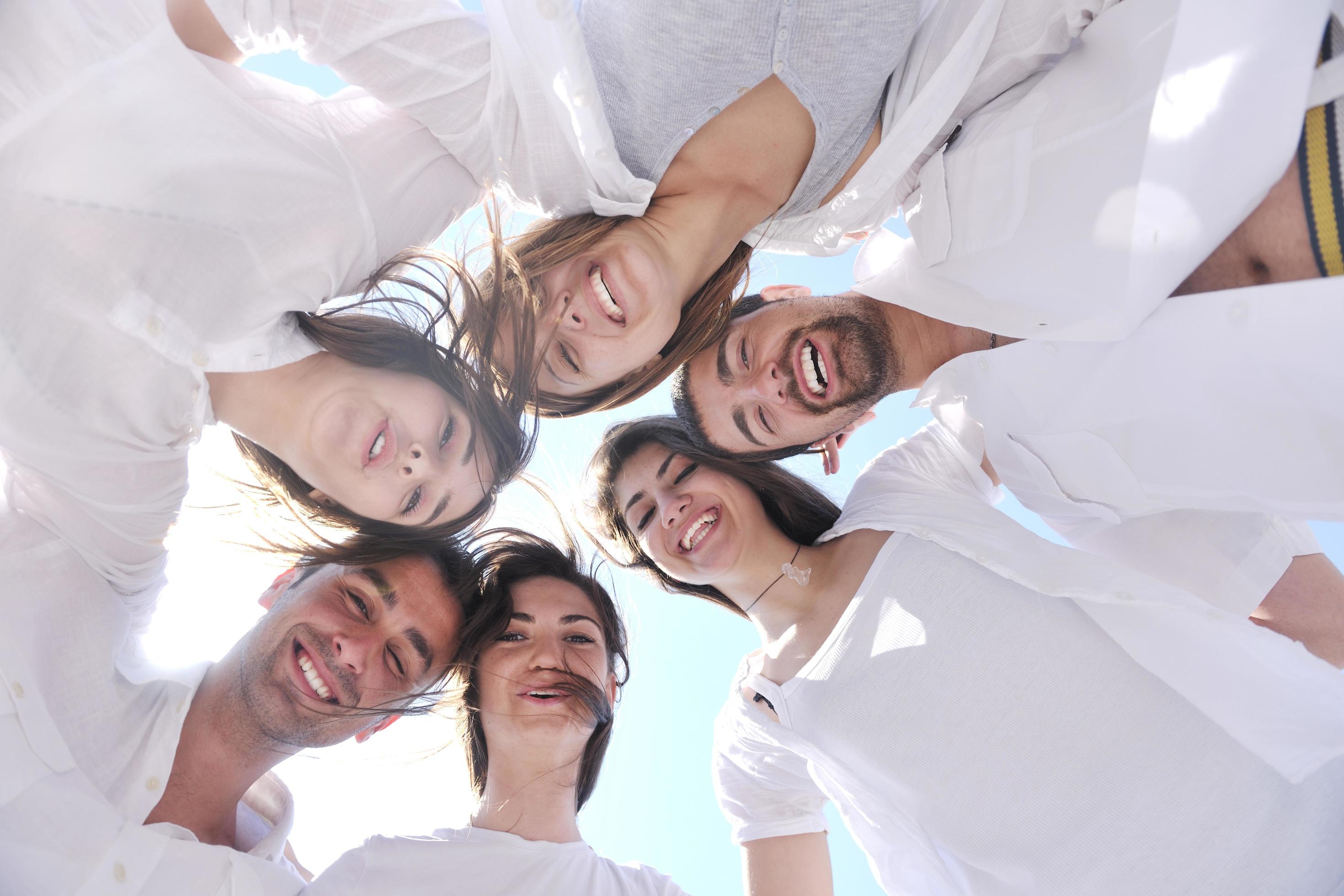 Group of happy young people in circle at beach Stock Free