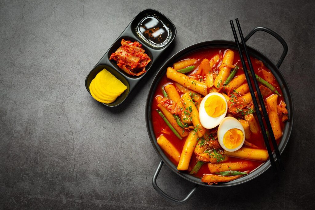 Cheesy Tokbokki korean traditional food on black board background. Lunch dish. Stock Free