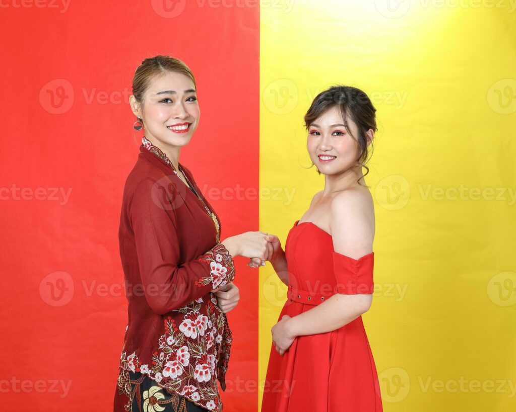 Two Asian woman traditional kebaya and modern dress red yellow paper background meet great Pro Photo