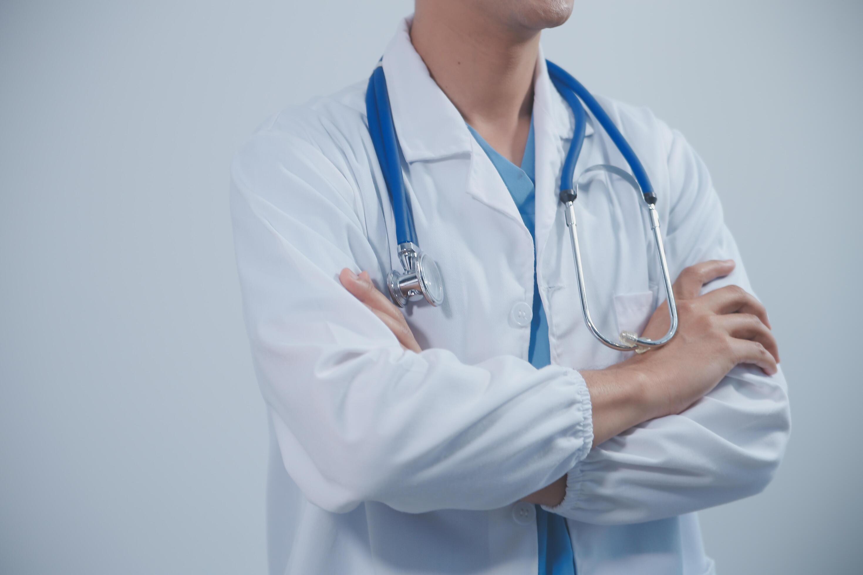 Mature male doctor with tablet pc is giving presentation. Blurred background indoors. Stock Free