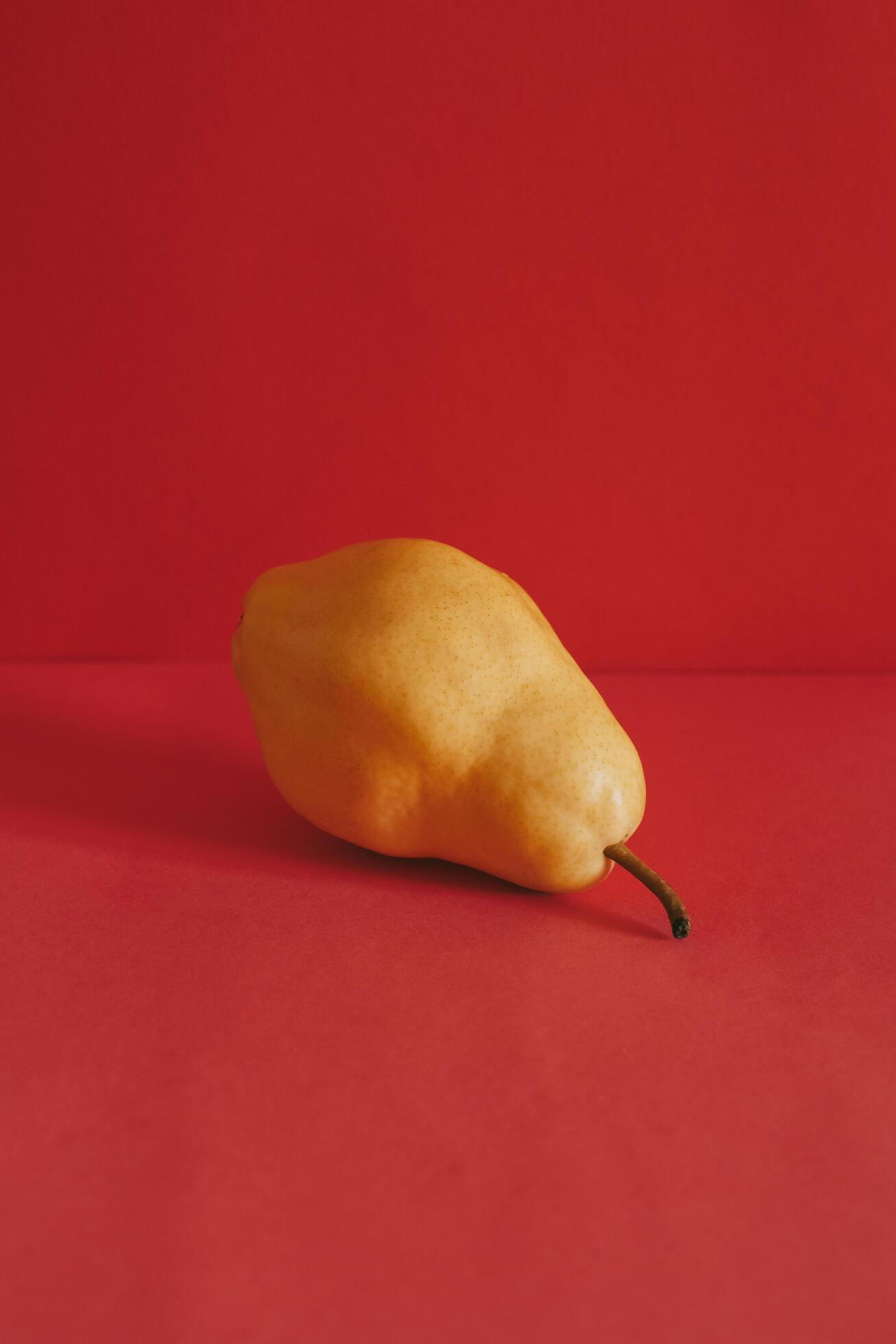 Ripe yellow pear on a bright red background. Stock Free