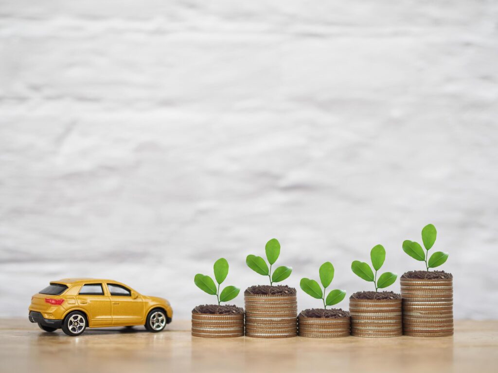 Toy car and plants growing up on stack of coins. The concept of business growth, saving money and manage to success transport business Stock Free