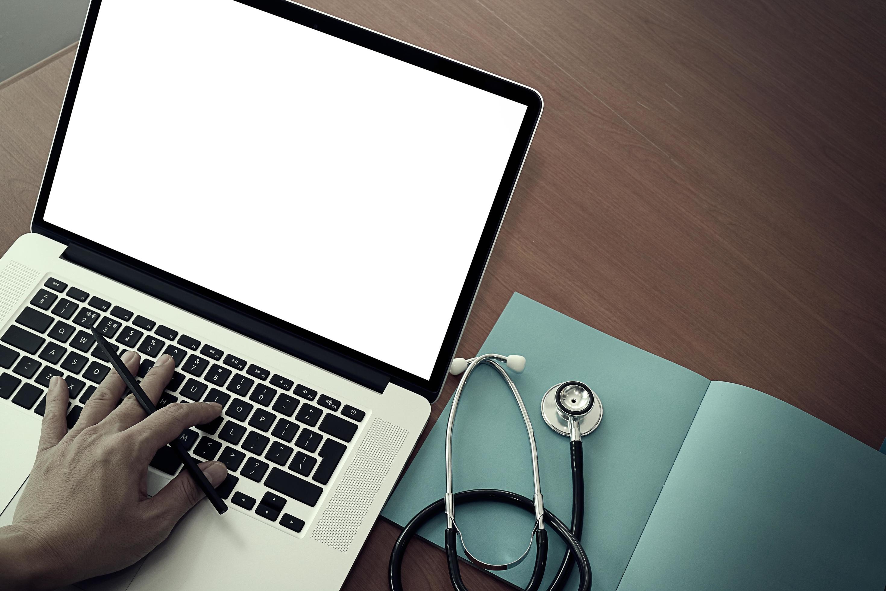 top view of Medicine doctor hand working with modern computer and blank screen on wooden desk as medical concept Stock Free