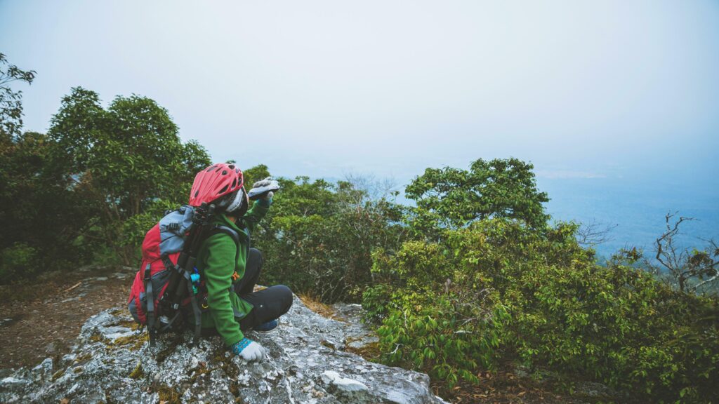 Asian woman travel nature. Travel relax. Sit and watch nature landscapes on the cliff. Vacation on the mountains. Stock Free