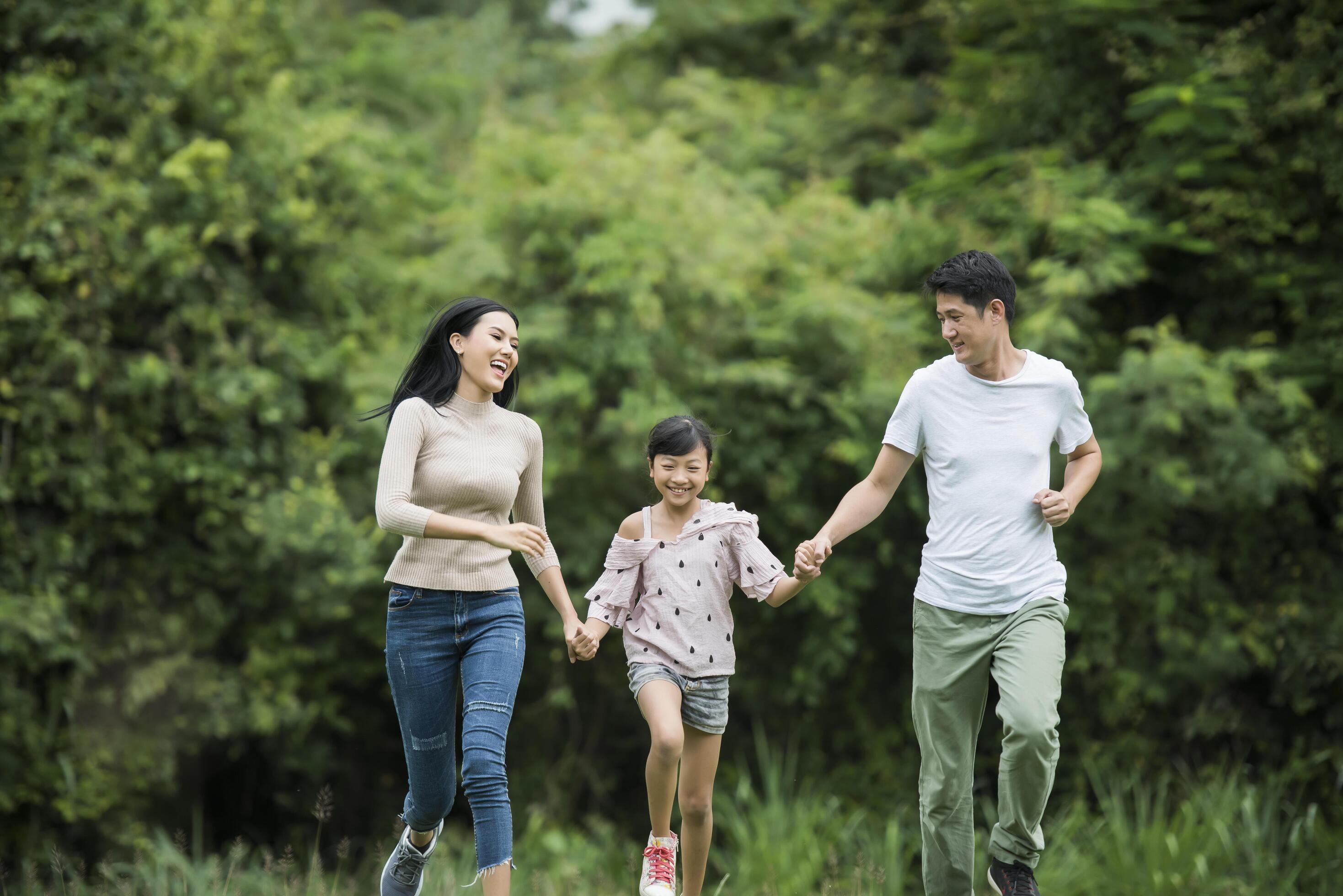 Happy family is having fun Mother, father and daughter are running in park. Stock Free