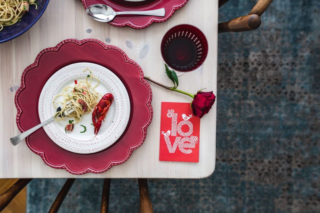 
									Fancy dinner with seafood pasta, crayfish and red wine by the table decorated with roses Stock Free