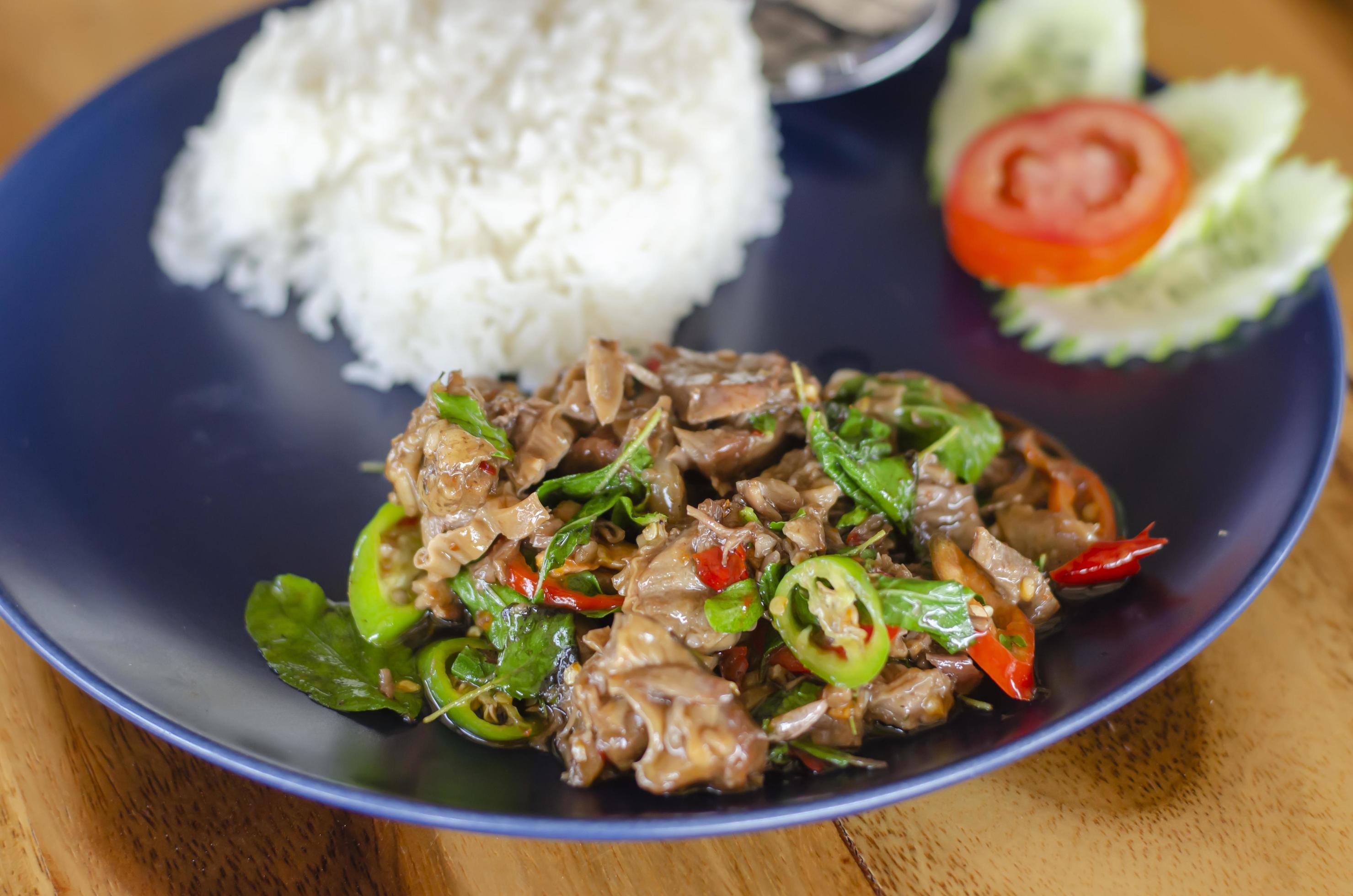 Stir Fried Basil with Stewed Pork on Rice popular traditional Thai food with wooden table background. side view Stock Free