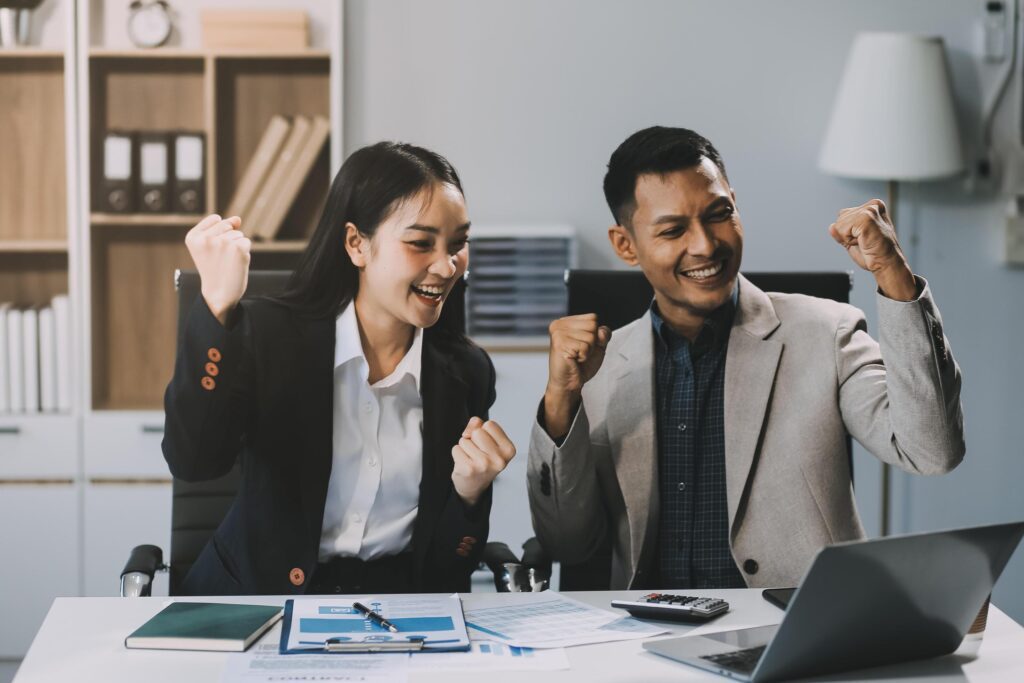 Young asian business woman giving high five with friends while working with computer laptop at office. Stock Free