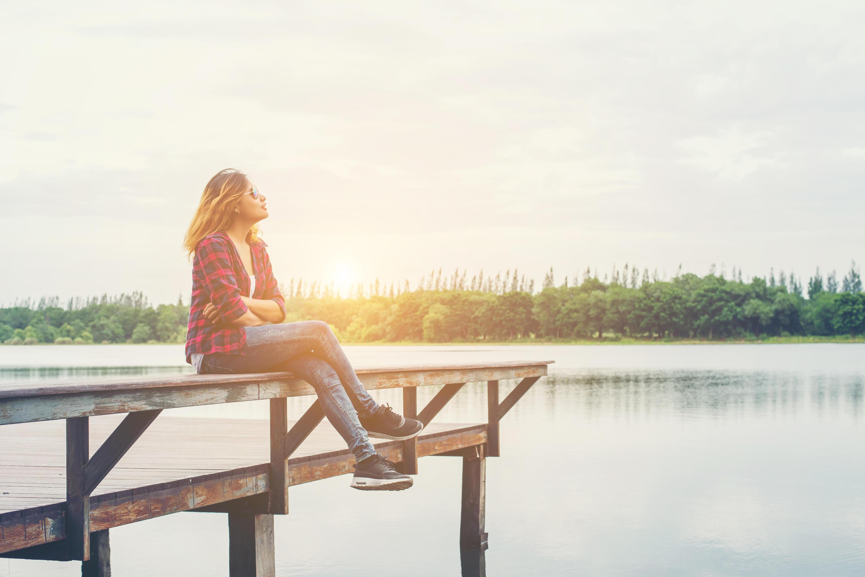 Young hipster woman sitting on pier,relaxing with natural freedom,enjoy and happy. Stock Free