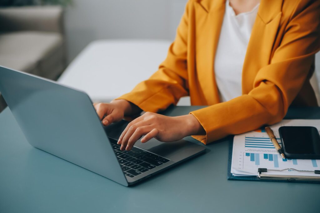 Happy millennial caucasian lady in suit typing on tablet at workplace with laptop in light office interior. Manager work, business with device, app, chat with client remotely Stock Free