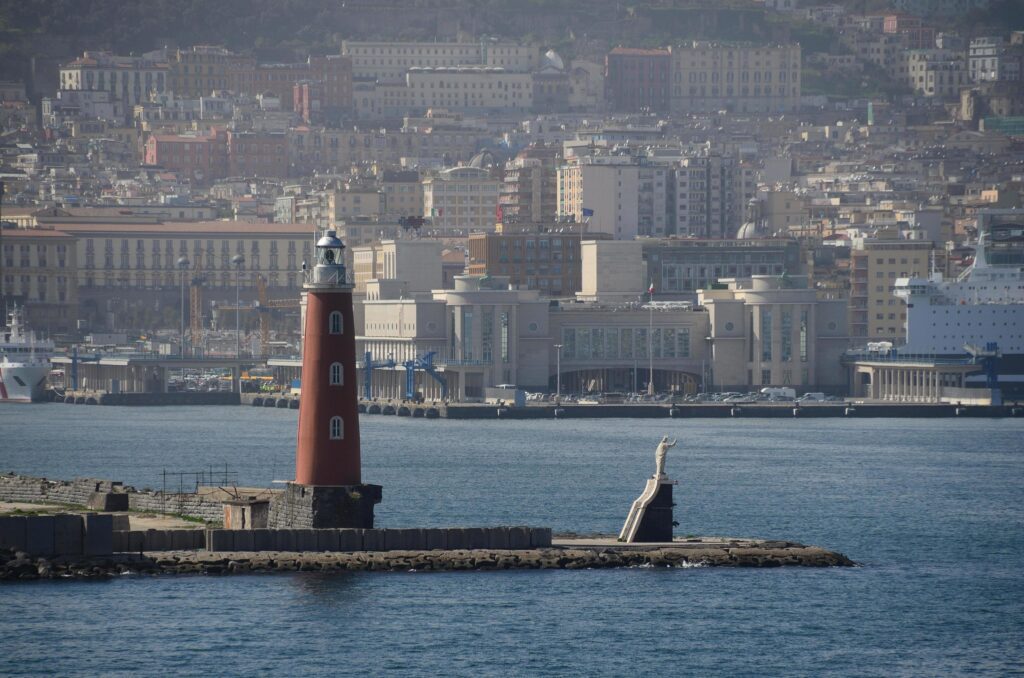 lighthouse with statue in the harbor Stock Free