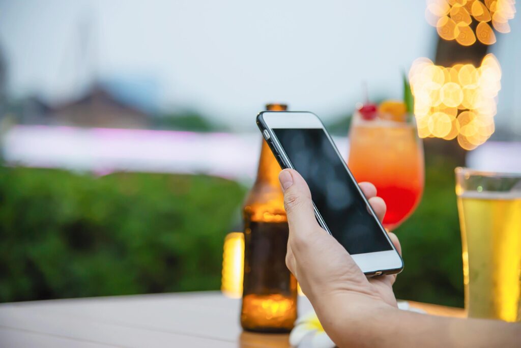 Man using mobile during happy time relax in restaurant with softdrink and green garden background – people relax with technology lifestyle concept Stock Free