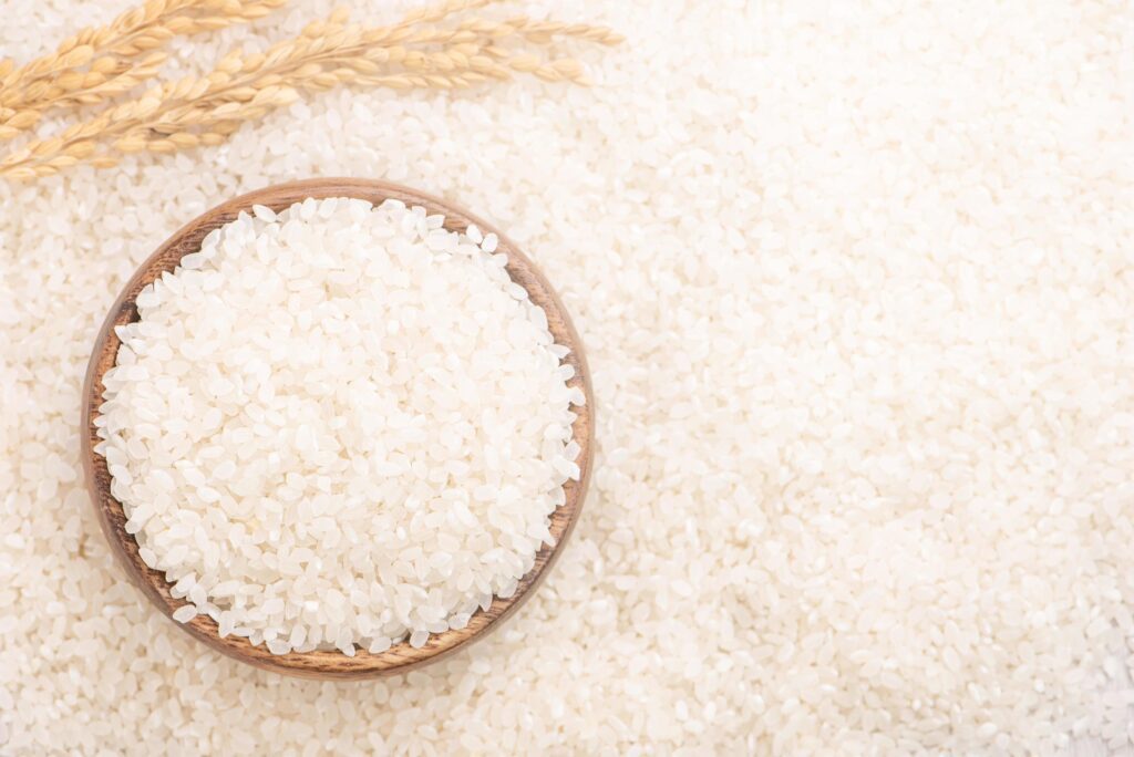 Raw white polished milled edible rice crop on white background in brown bowl, organic agriculture design concept. Staple food of Asia, close up. Stock Free