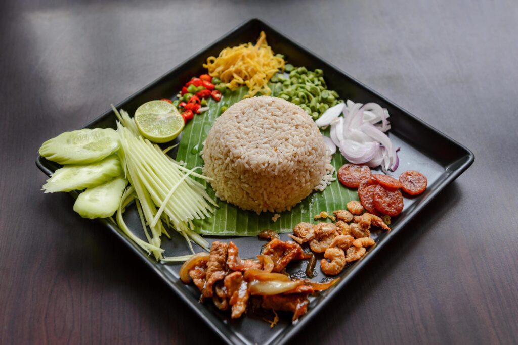 Thai food – Rice mixed with shrimp paste, Kao Cluk Ka Pi with side dish as a mango, lemon, chili, cucumber, scrambled egg, cow-pea, shallots, Chinese sausage, dried shrimp and pork Stock Free