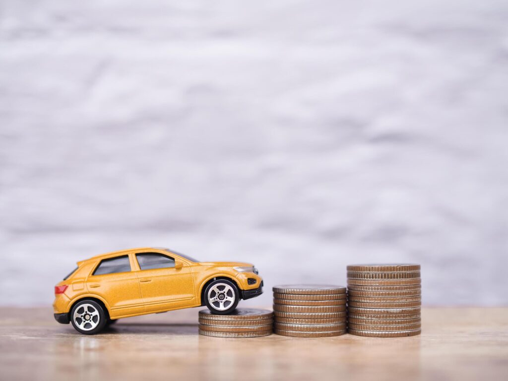 Toy car and stack of coins. The concept of saving money and manage to success transport business Stock Free