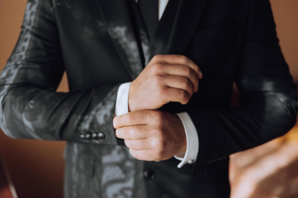 young smiling man buttoning up his jacket in the morning before the wedding. close-up of a man in a business suit. Businessman puts on a suit. A man fastens the buttons on his jacket. Stock Free