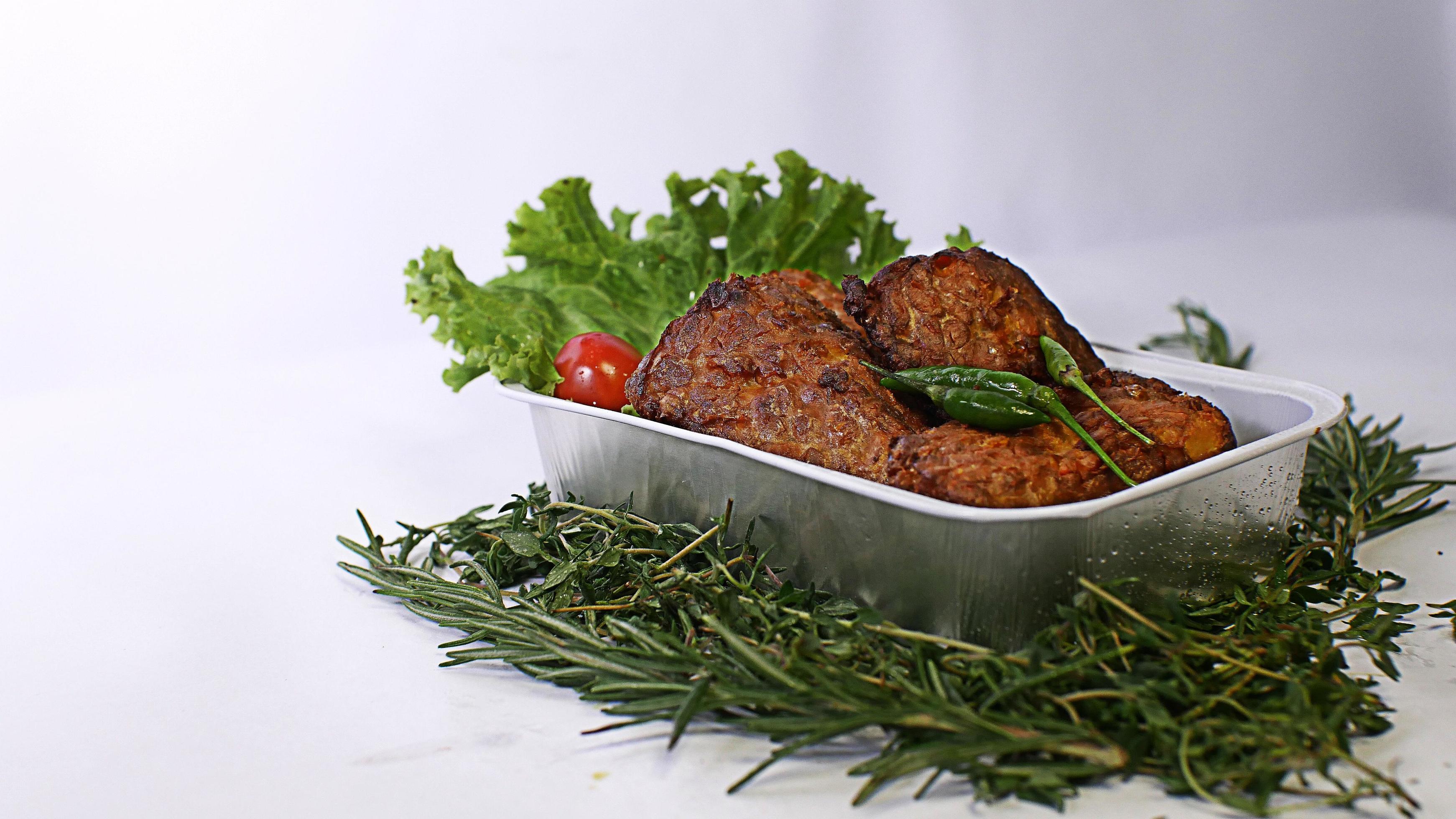 Fried soybean mushrooms, small tomatoes, chilies and salad in one aluminum container. typical indonesian street food on a white background Stock Free