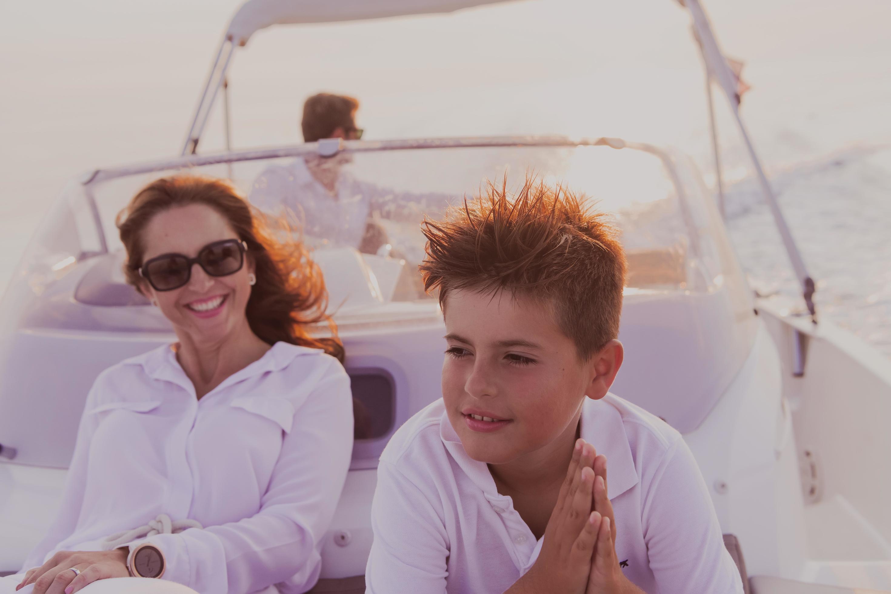 A senior couple in casual outfits with their son enjoy while riding a boat at sea at sunset. The concept of a happy family. Selective focus Stock Free