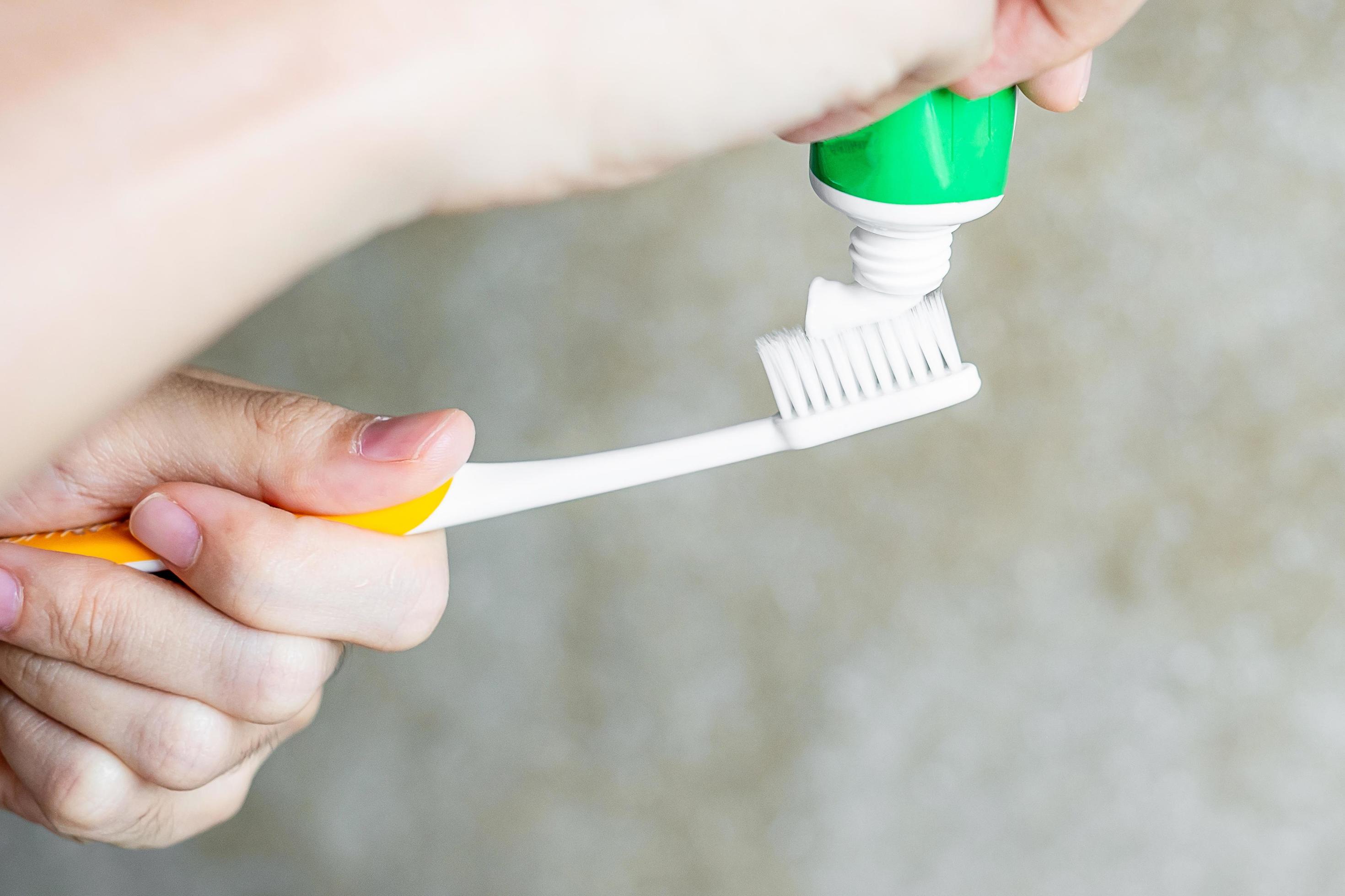 Hand holding Toothbrushes with toothpaste in bathroom. Lifestyle, daily routine, World oral health day and free dental day concept Stock Free