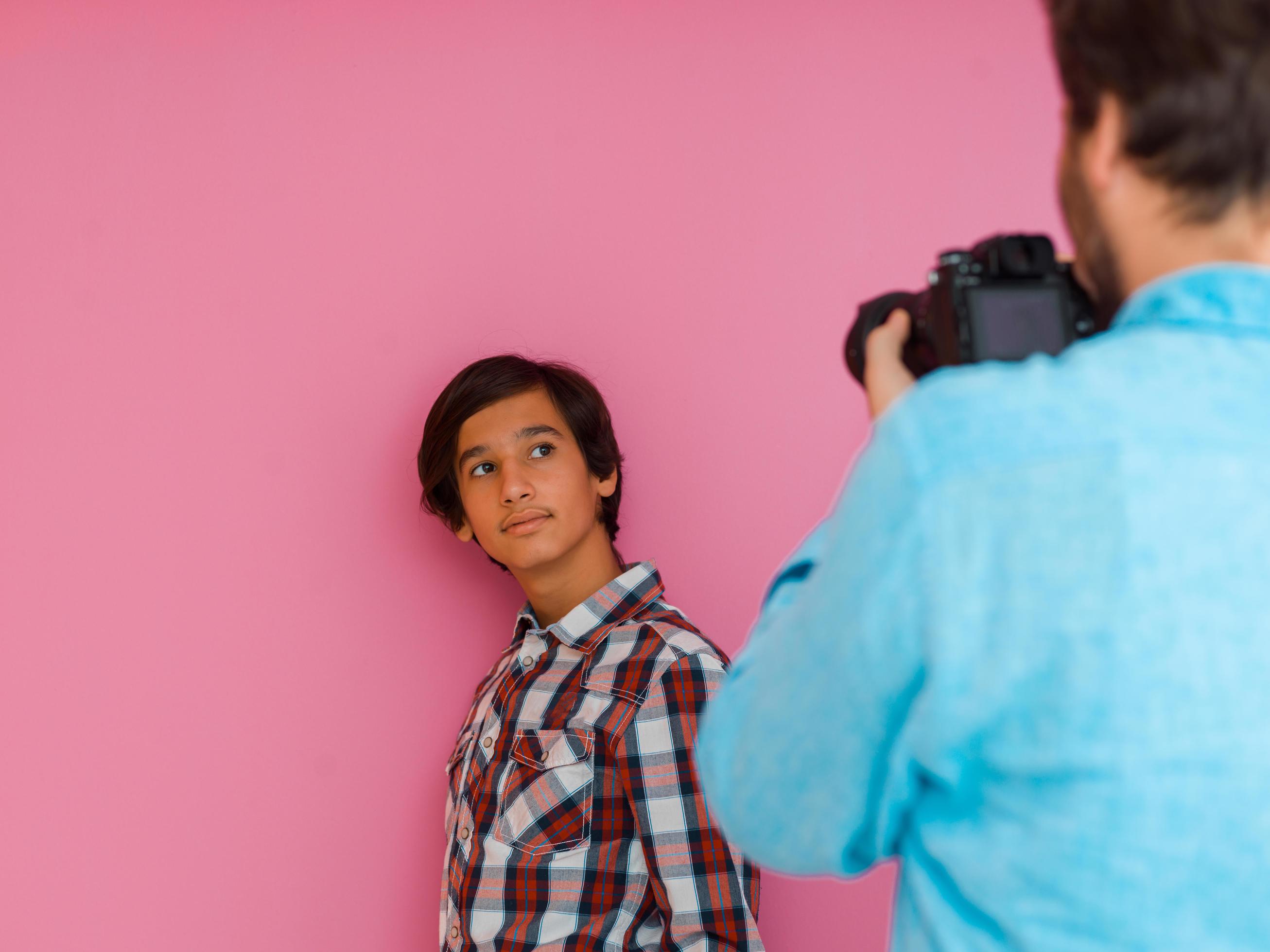 A photo of a father and son taking family photos in the house in front of a purple wall. Selective focus Stock Free