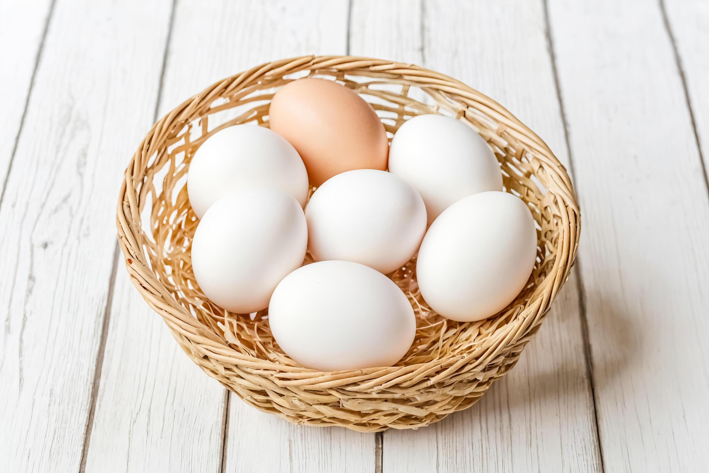 Fresh white eggs in a wicker basket on white wooden background Stock Free