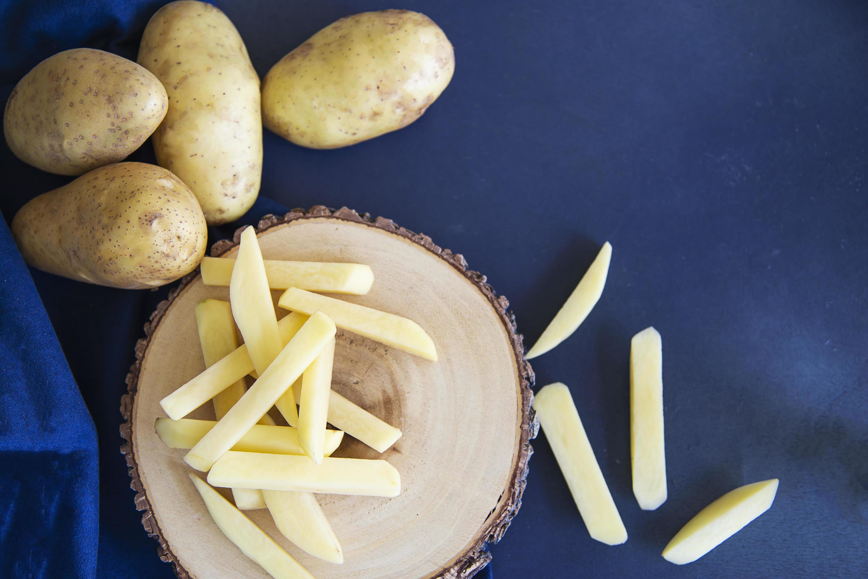 Sliced potato stick ready for making French fries – traditional food preparation concept Stock Free