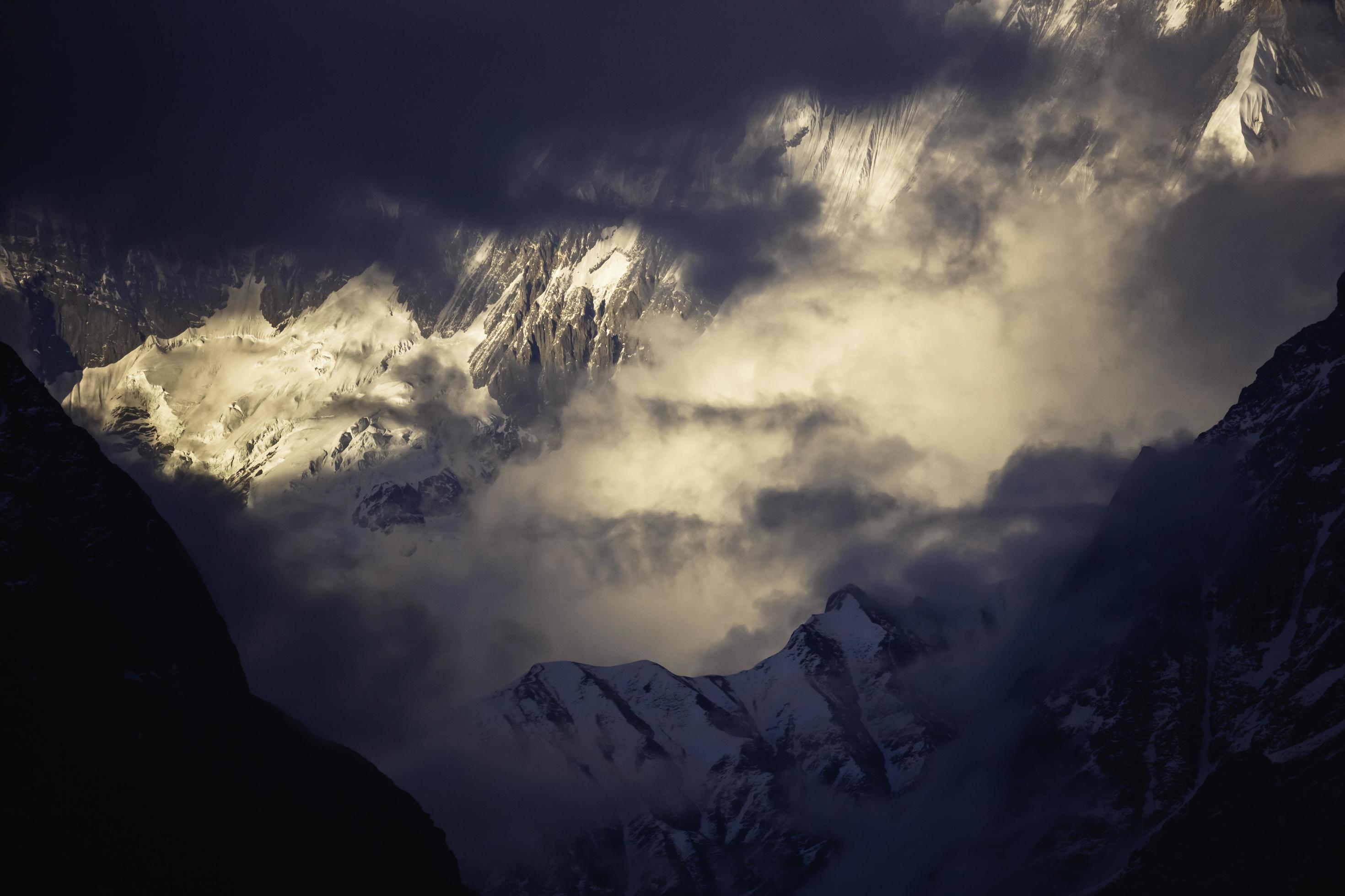 Sunlight and clouds mingle to create a dramatic landscape over the Annapurna mountains on the Annapurna Base Camp trail in the Nepal Himalayas. Stock Free