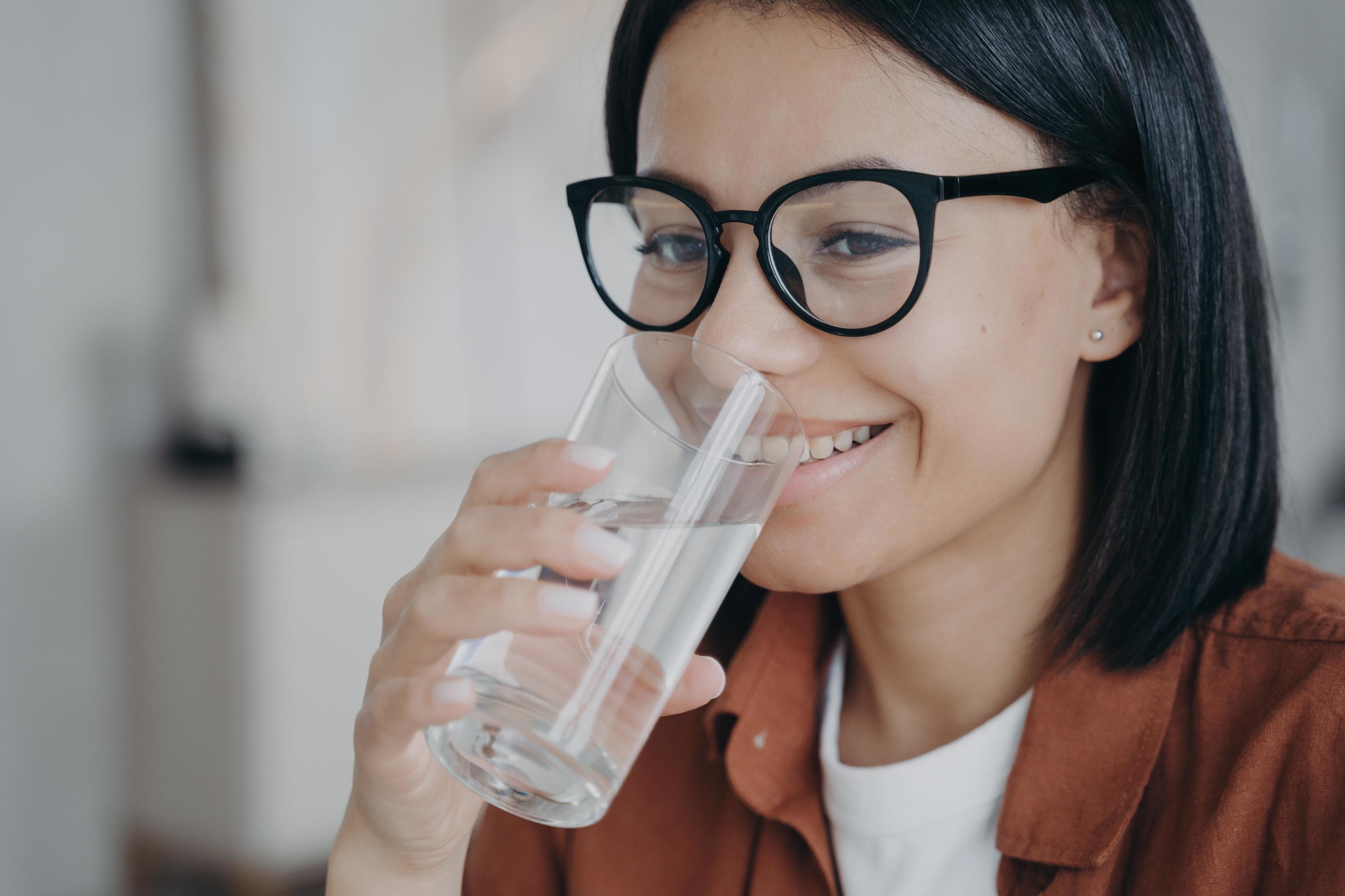 Happy thirsty young woman in glasses holding glass, drinking filtered clean water. Healthy lifestyle Stock Free