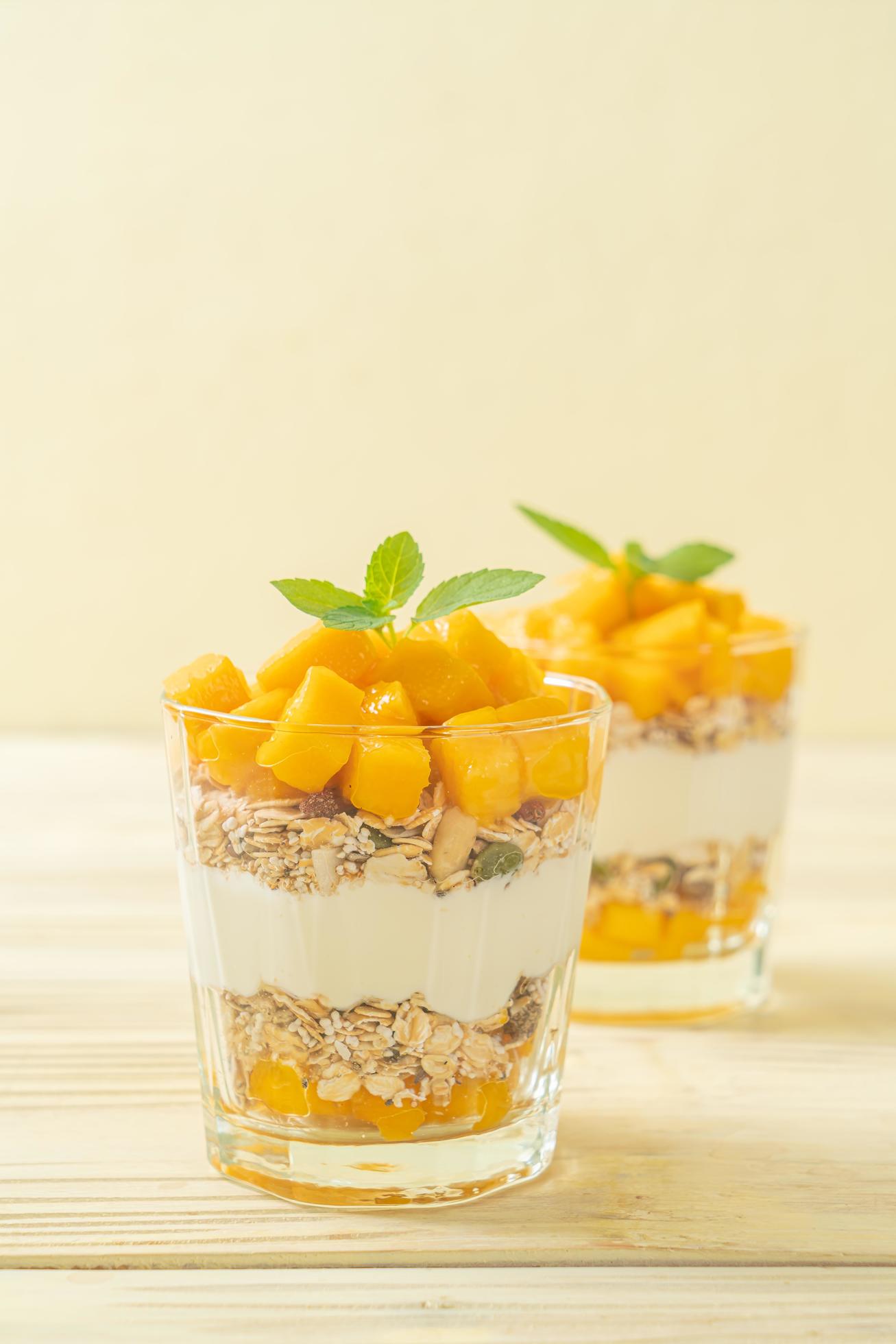 Fresh mango yogurt with granola in glass – healthy food style Stock Free