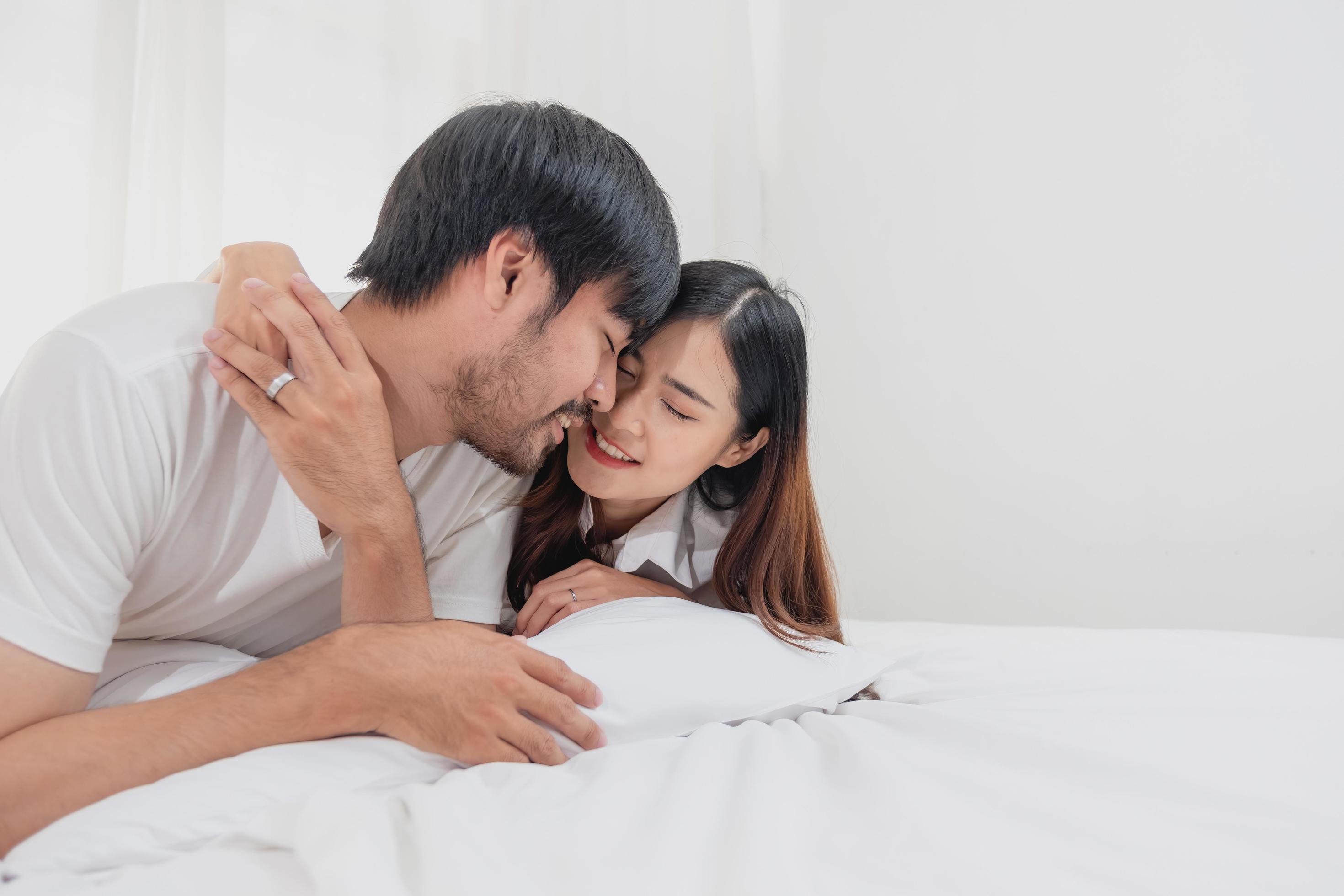 Happy young asian couple embracing, teasing, playing cheerfully in bed at home, romantic time to enhance family bonding. family concept. Stock Free