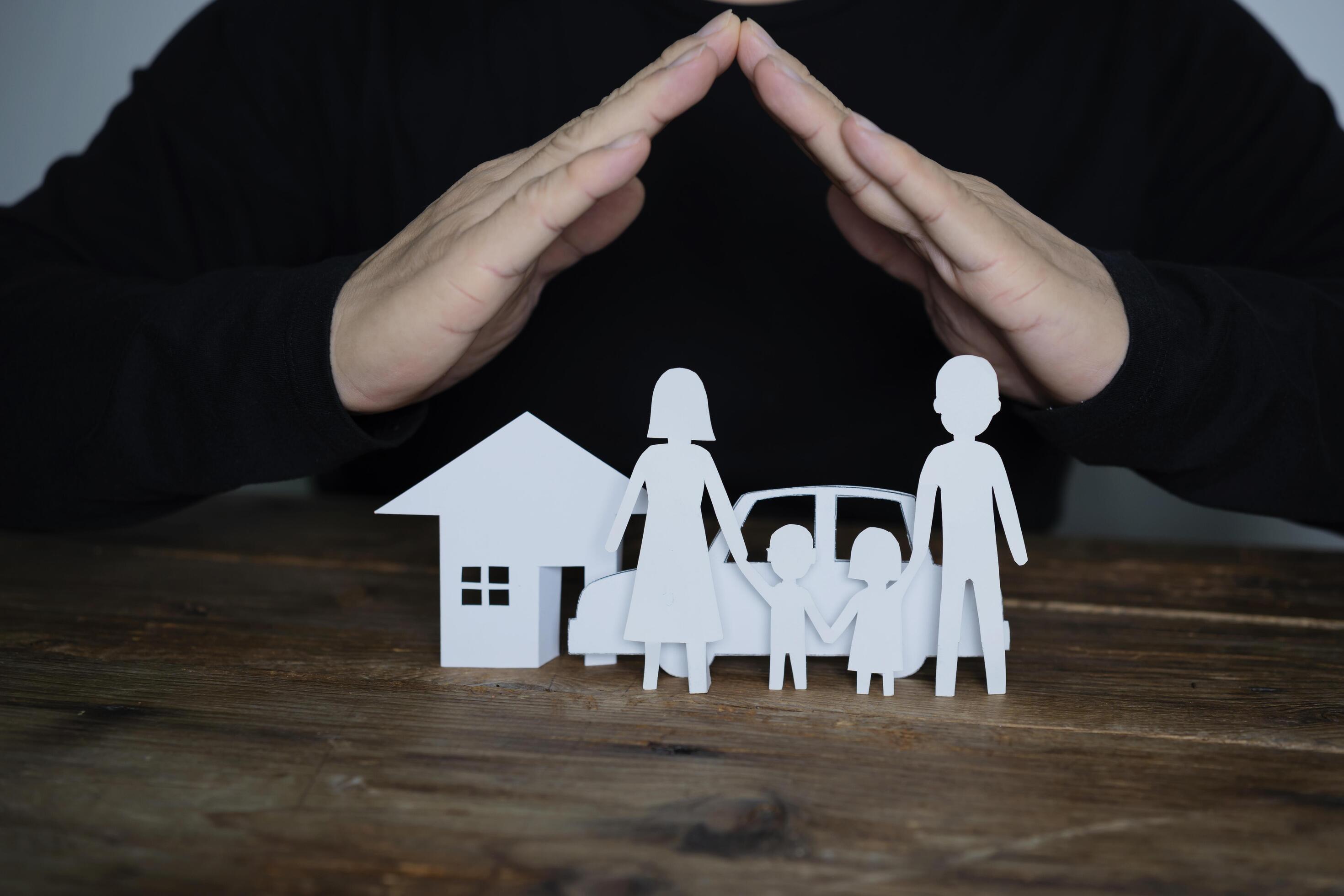 Concept of insurance with hands over a house, a car and a family Stock Free