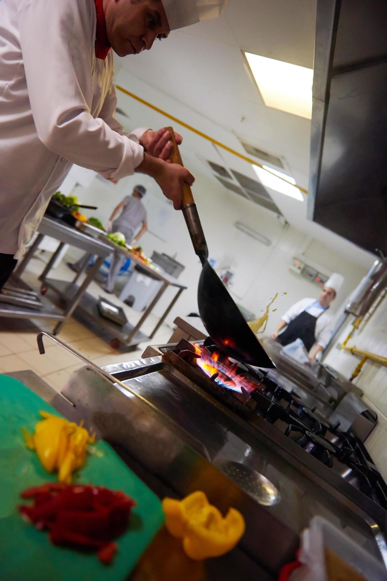 chef in hotel kitchen prepare food with fire Stock Free