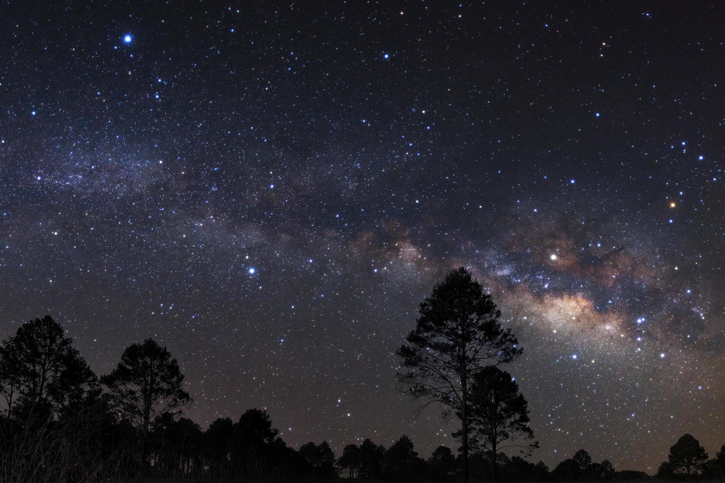 landscape with milky way, Night sky with stars and silhouette of a standing sporty man with raised up arms on high mountain. Stock Free