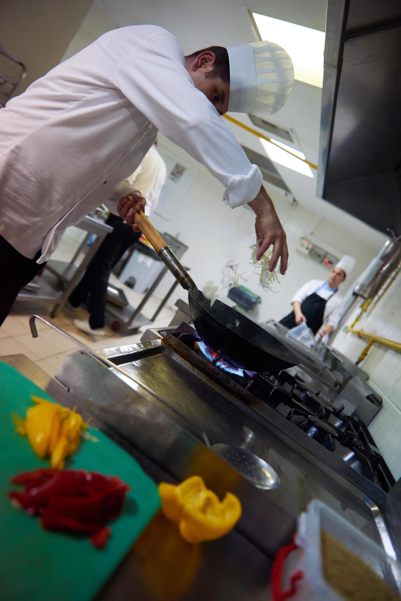 chef in hotel kitchen prepare food with fire Stock Free